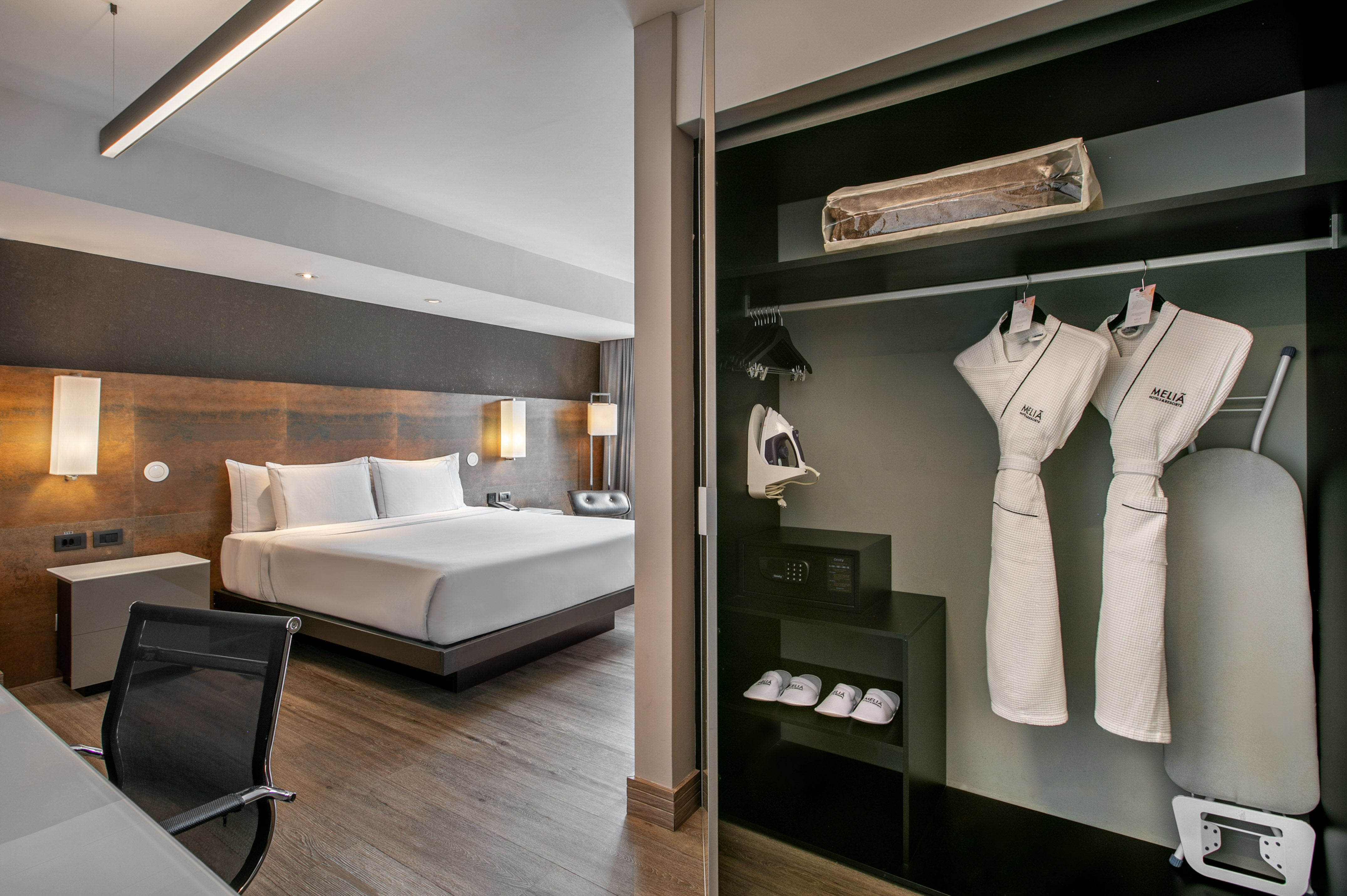 Quarto de hotel moderno com cama grande e armário aberto com roupões. - Grand Premium com Varanda - Meliá Ibirapuera, São Paulo
