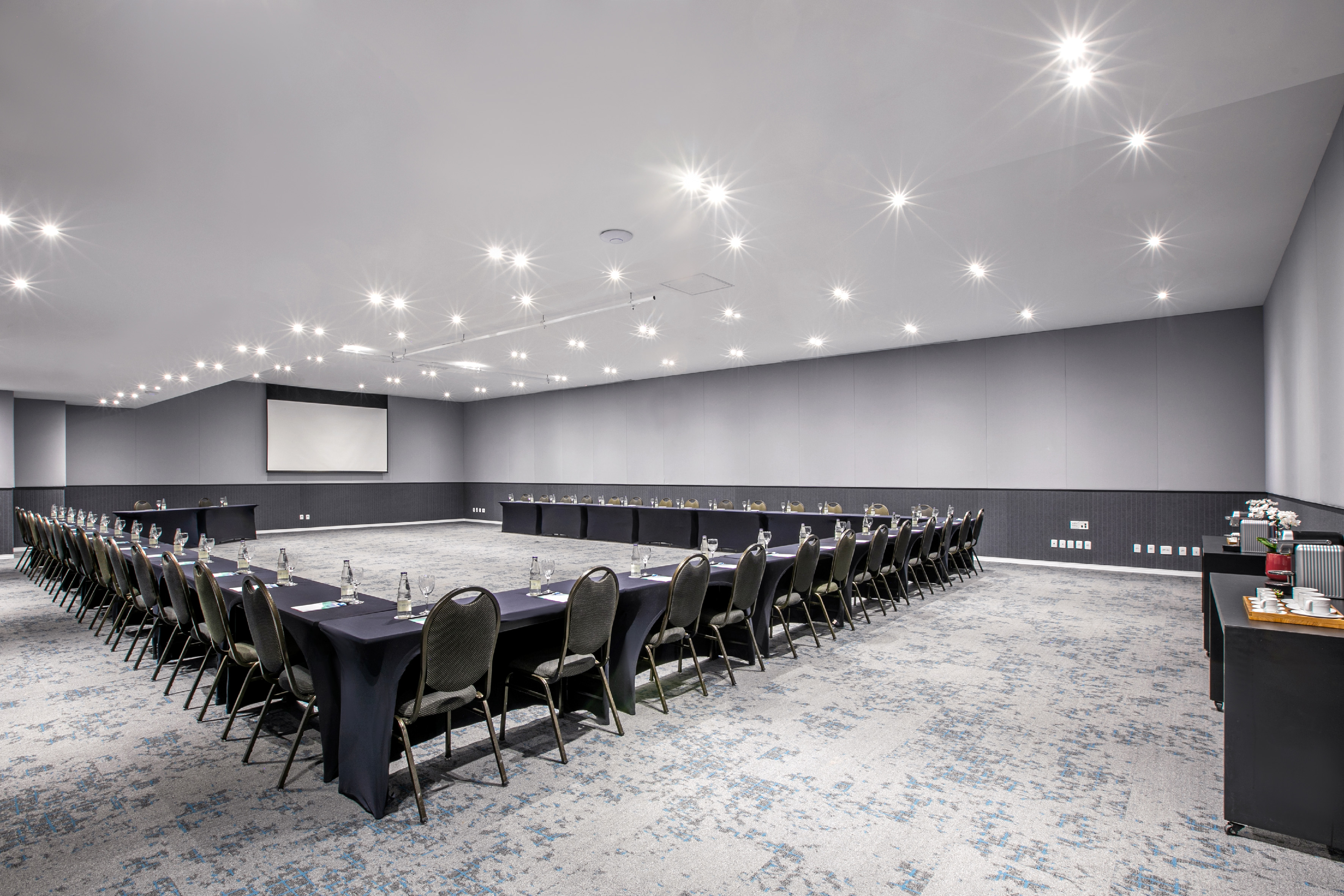 U-shaped conference room with tables, chairs, and projector screen.
