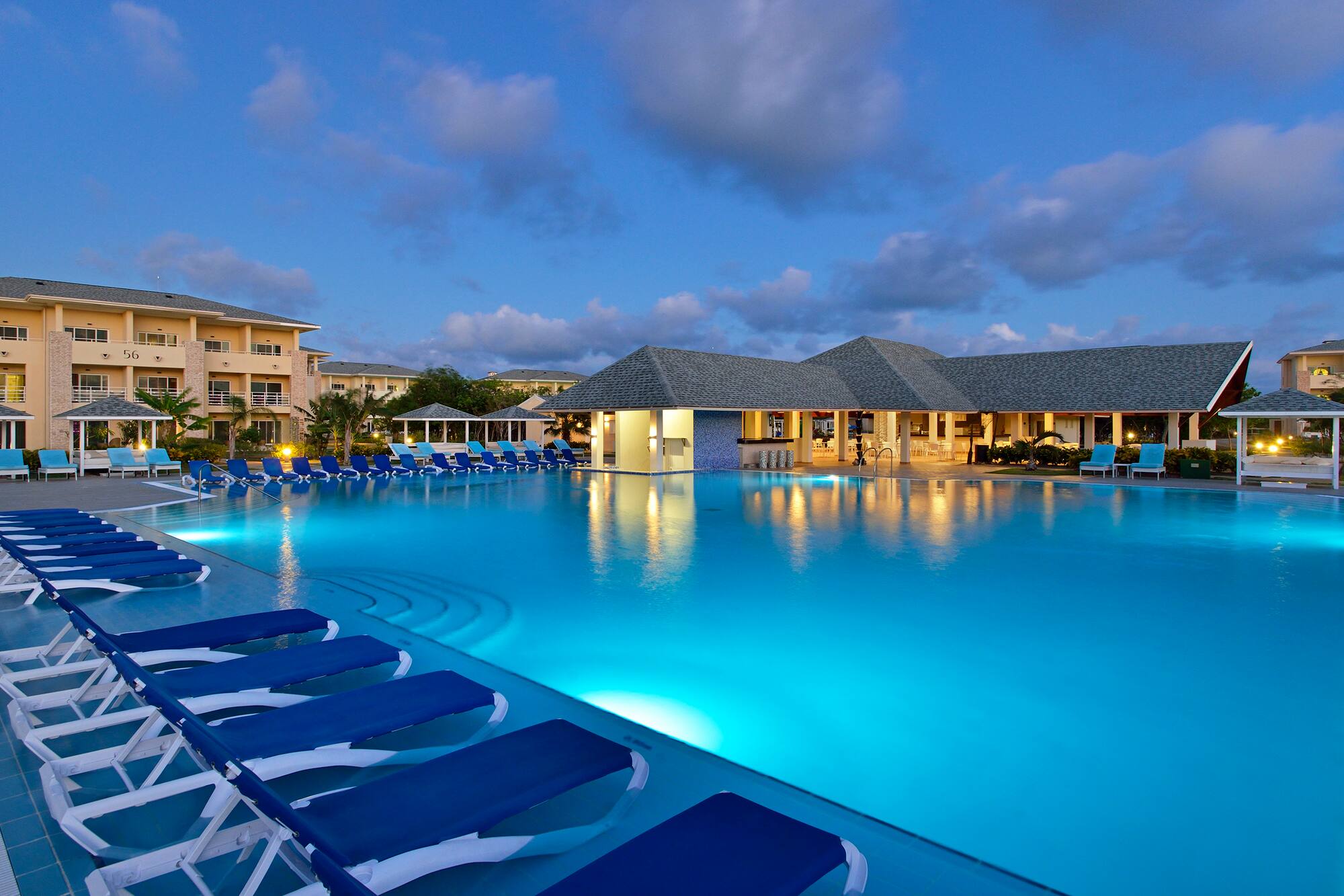 a pool with lounge chairs and a building