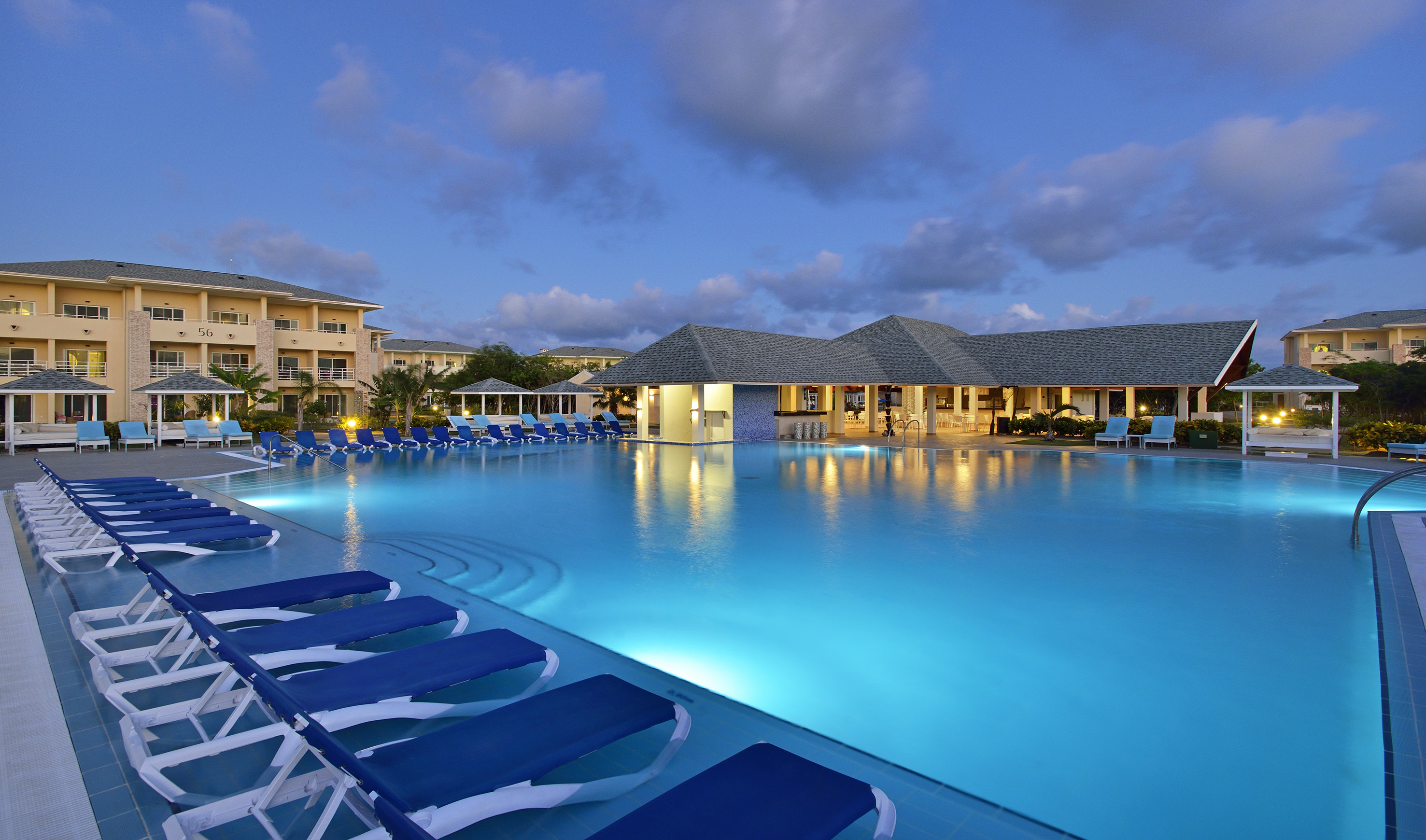 a pool with lounge chairs and a building