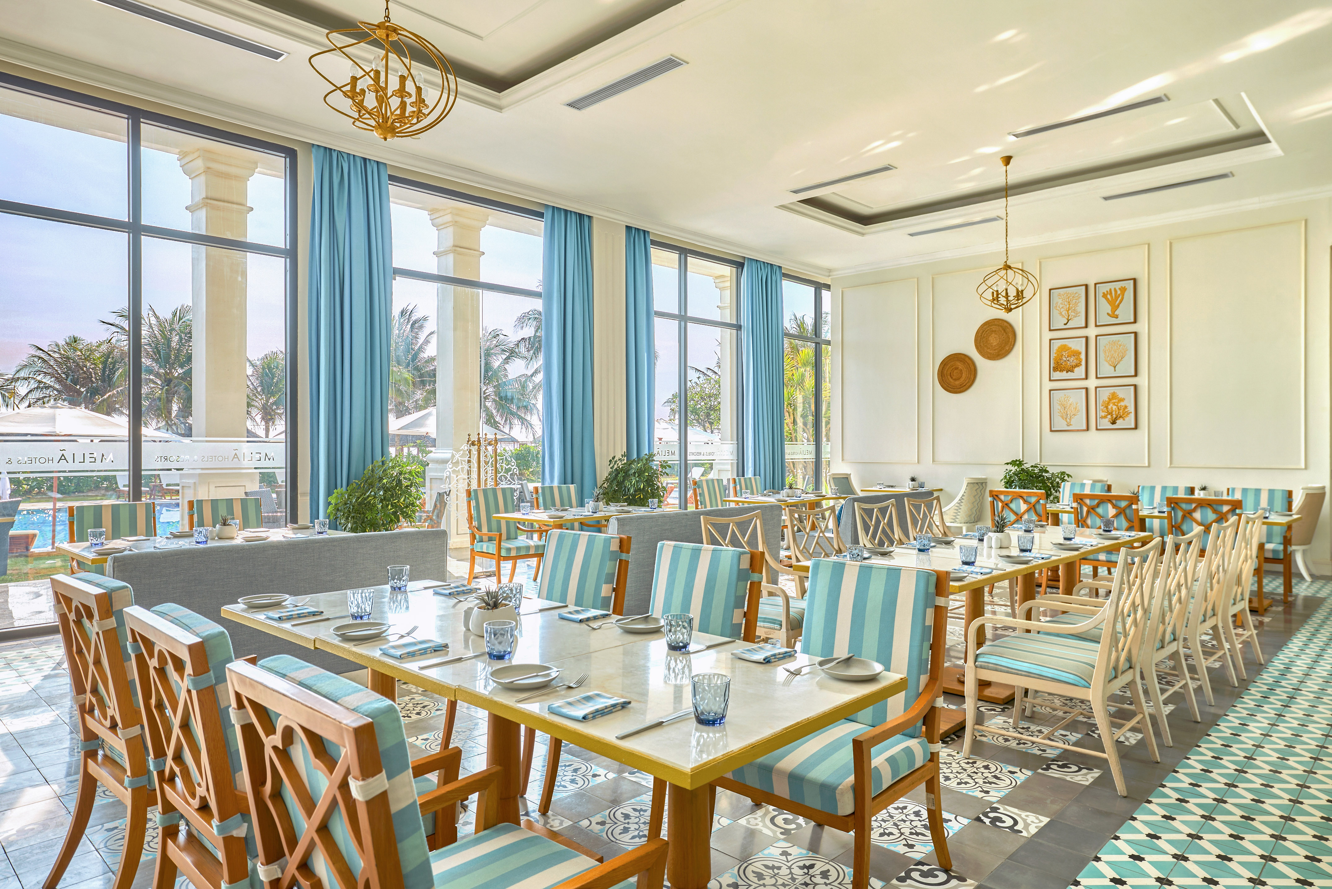 Hotel restaurant with blue and white decor, large windows, and palm tree view.