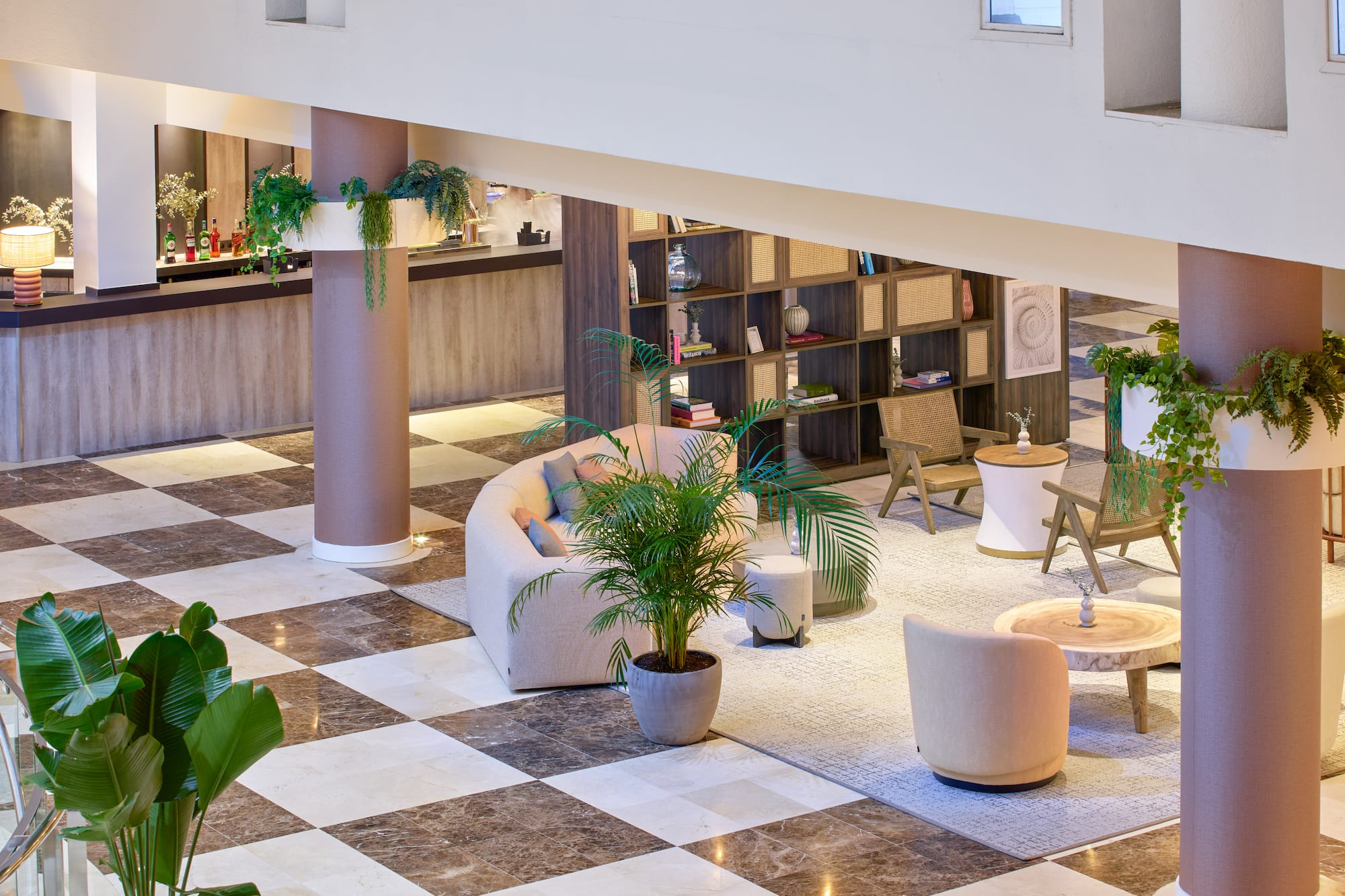 Modern hotel lounge with curved sofa, plants, bar, and marble checkered floor.