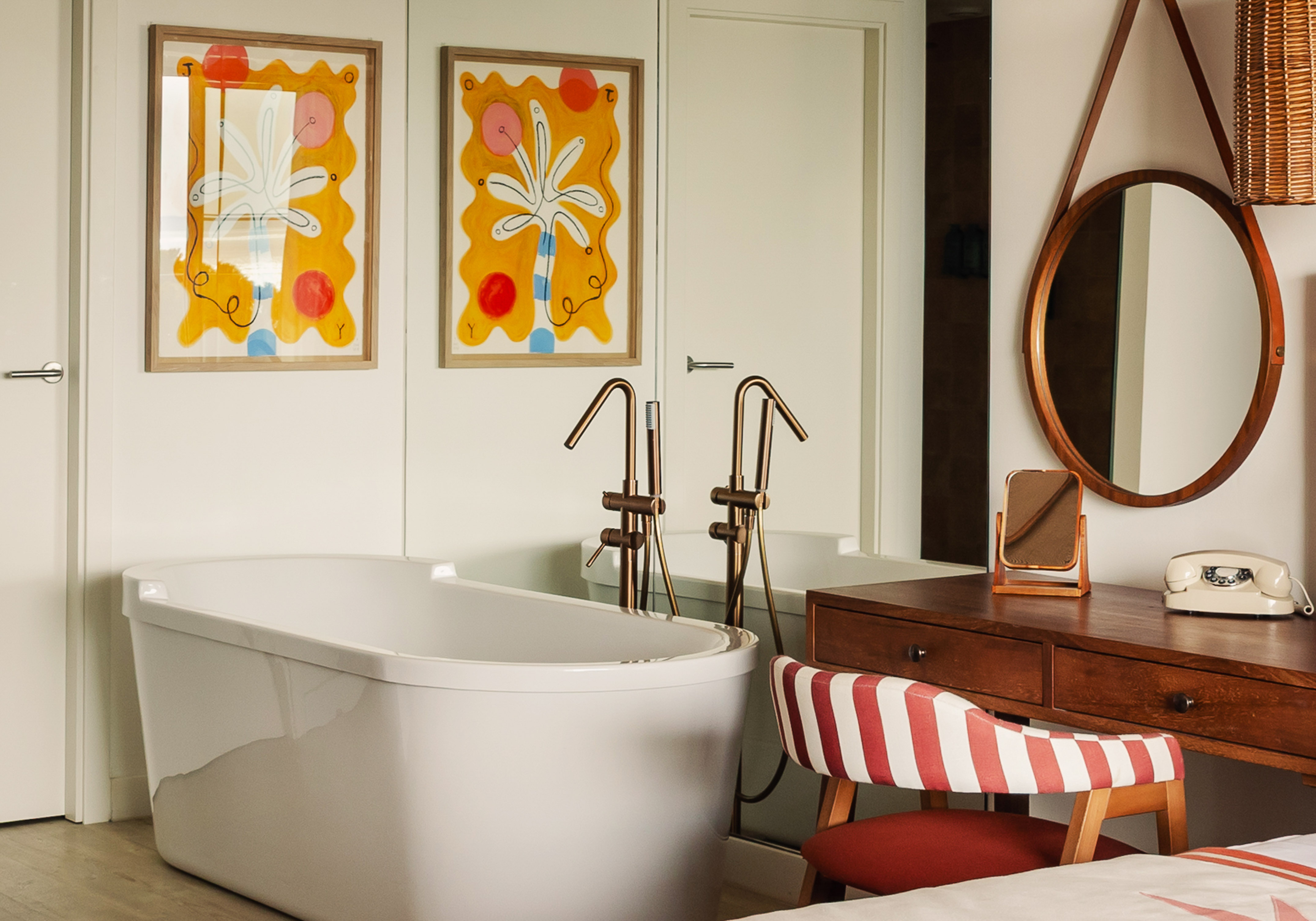 Modern room with freestanding tub, colorful abstract art, and retro desk.