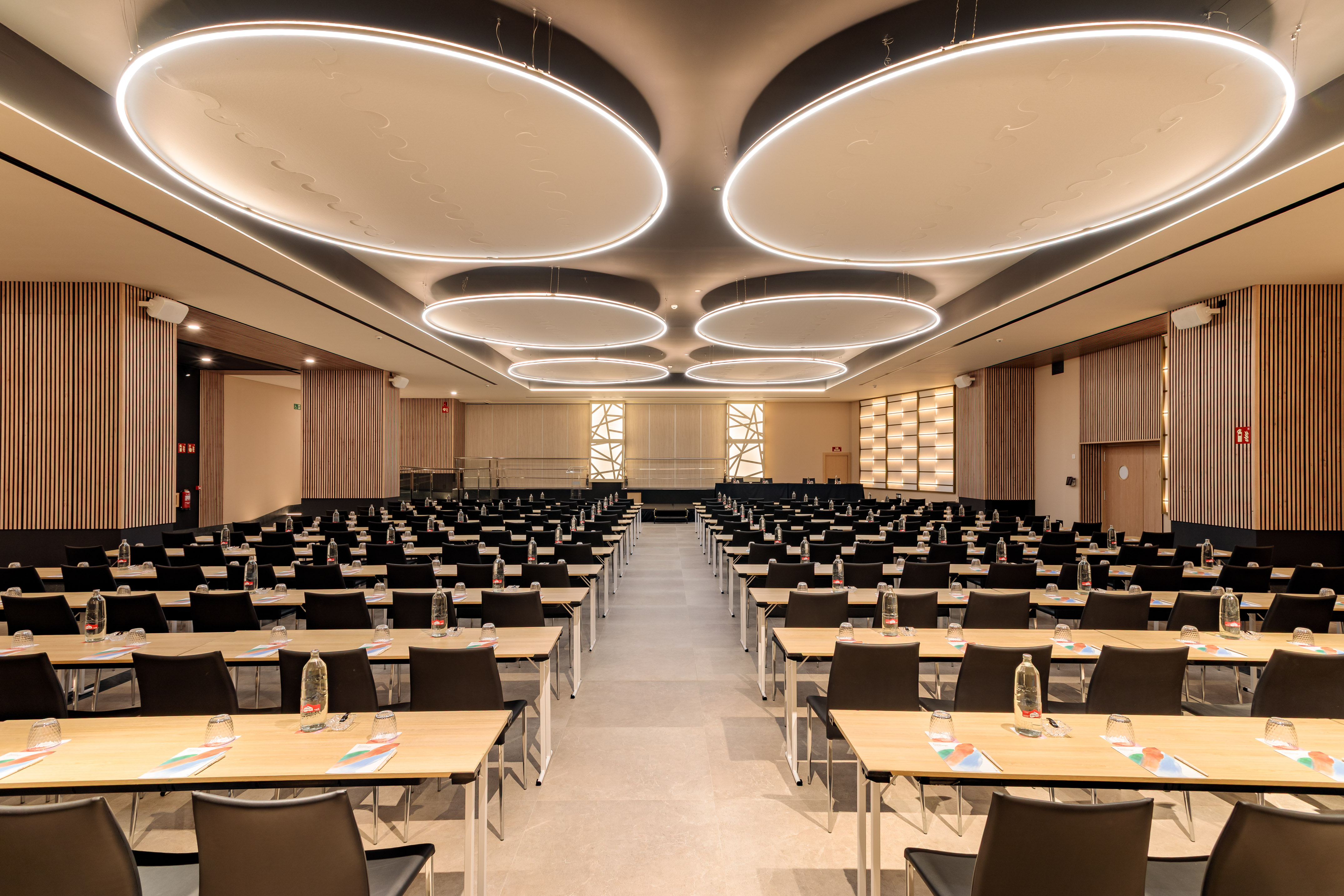 Modern business conference room with tables, chairs, and illuminated ceiling.