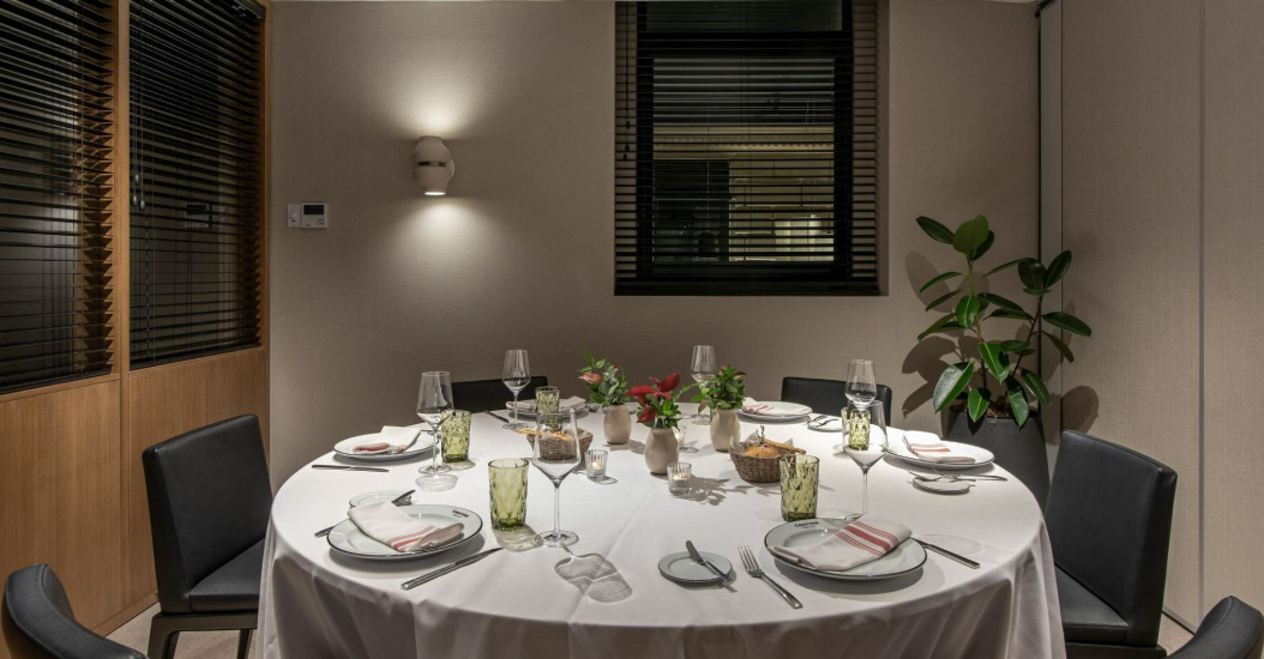 Round dining table set in a modern, elegant private dining room.
