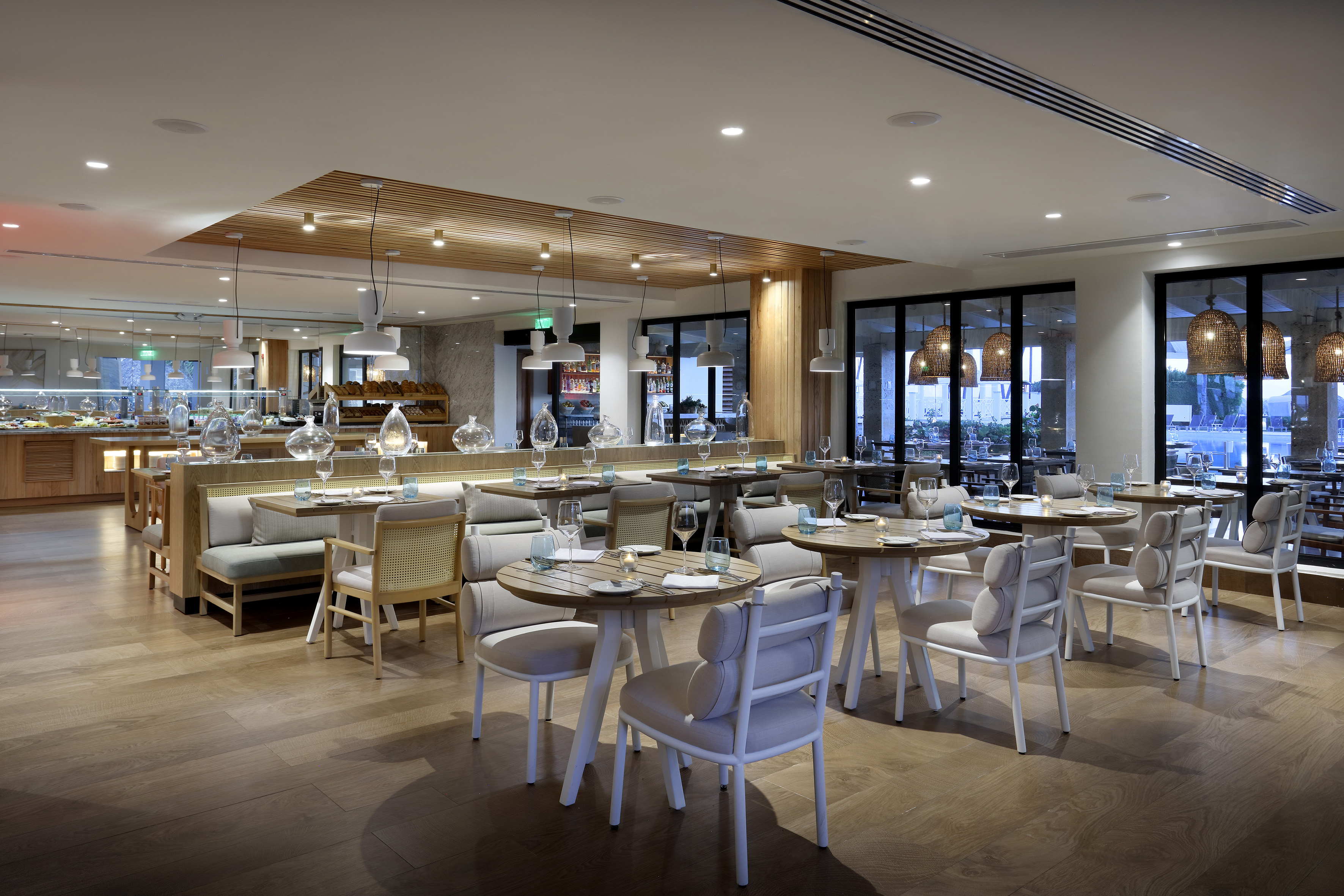 Modern restaurant dining with buffet, wood floors, stylish seating, pool view.