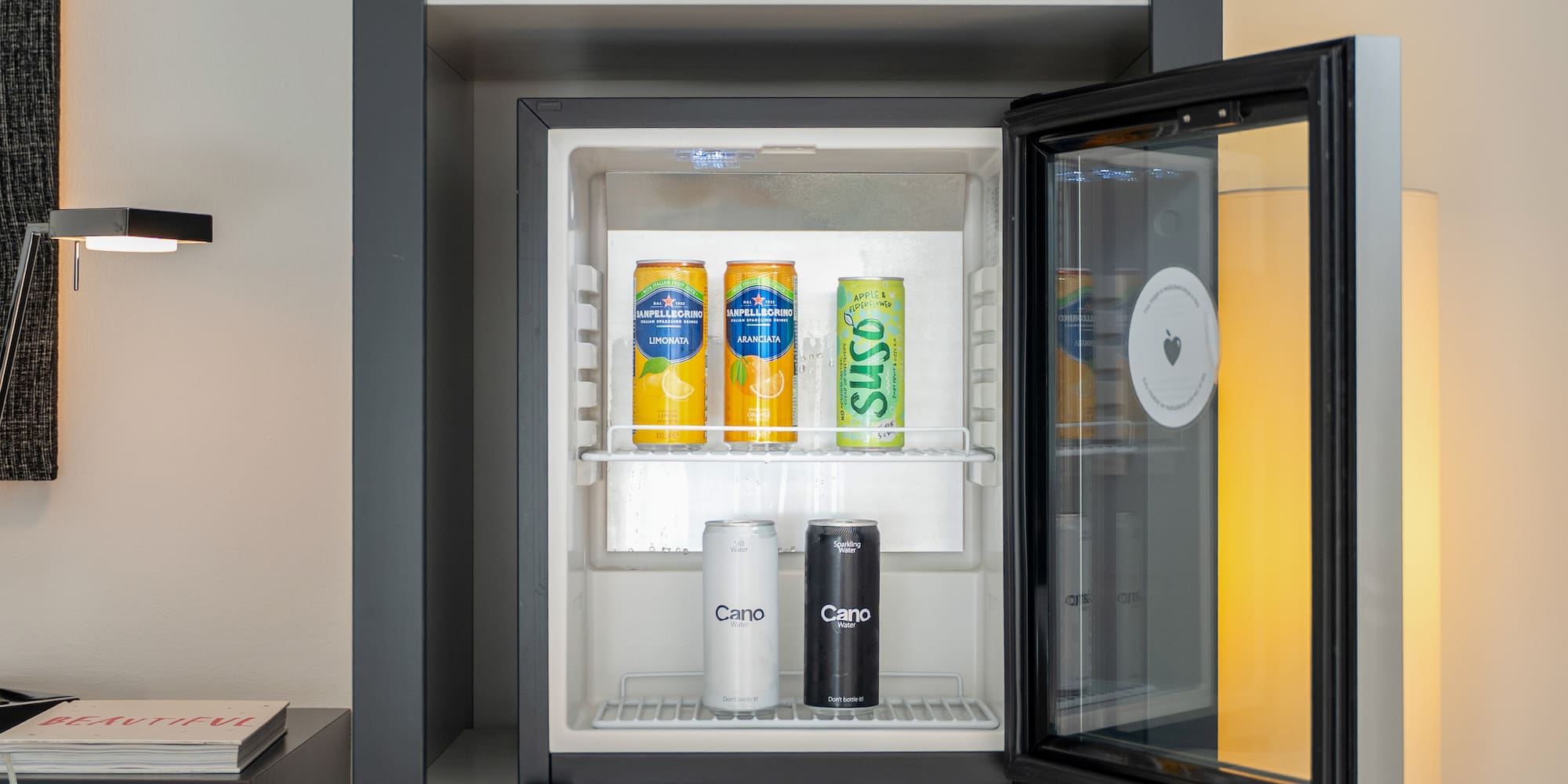 Modern minibar stocked with San Pellegrino, Suso, and Cano water.