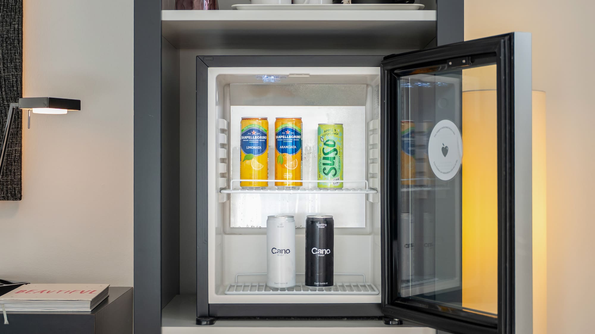 Modern minibar stocked with San Pellegrino, Suso, and Cano water.