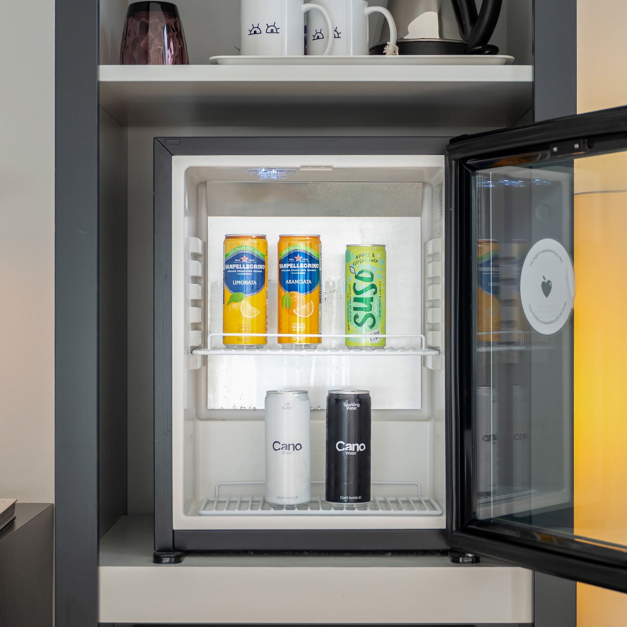 Modern minibar stocked with San Pellegrino, Suso, and Cano water.