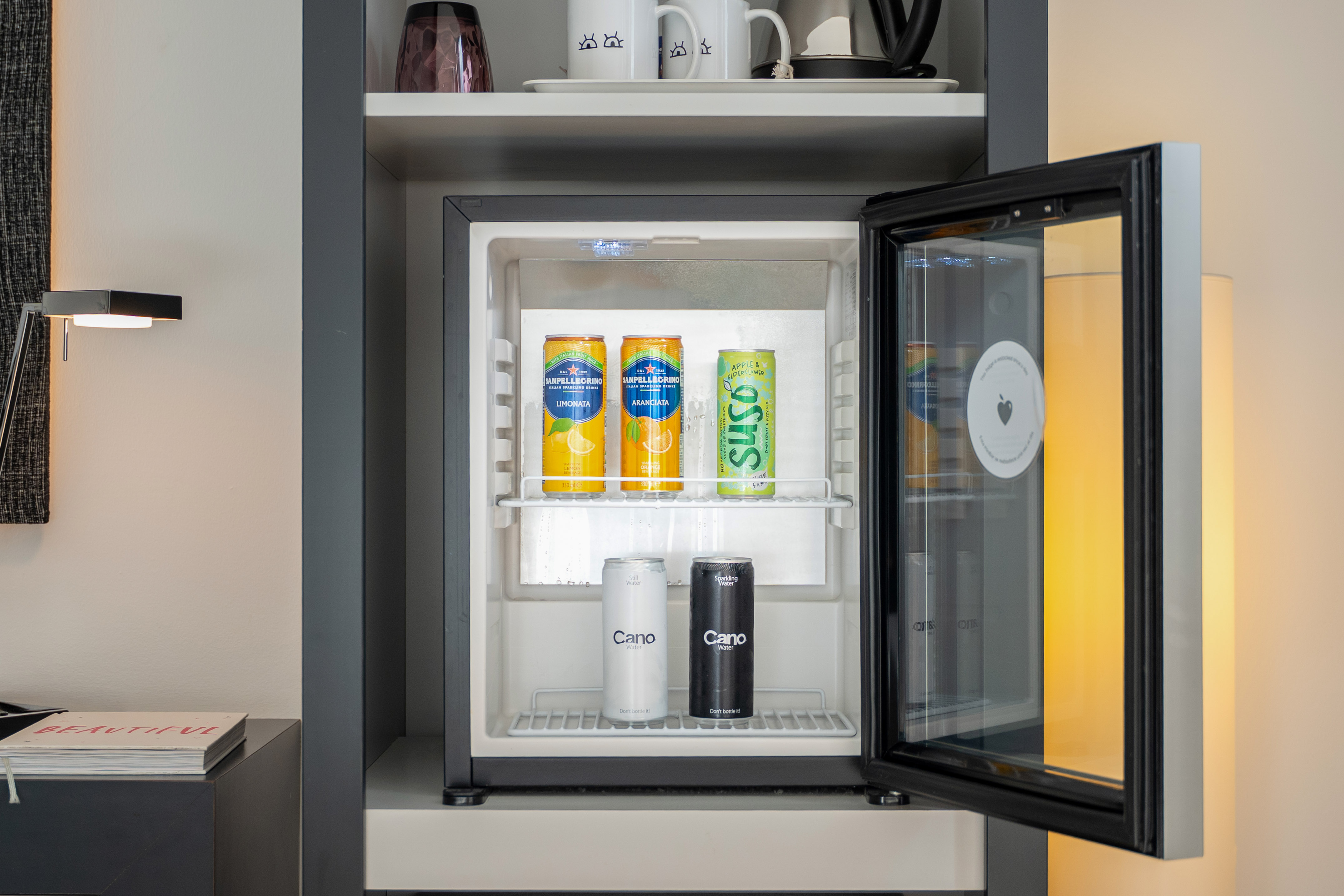 Modern minibar stocked with San Pellegrino, Suso, and Cano water.