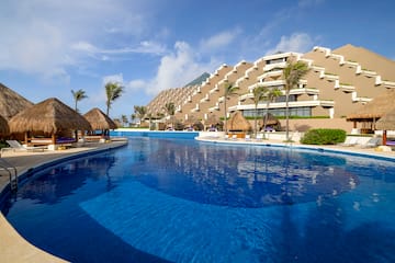a pool with straw umbrellas and a building in the background