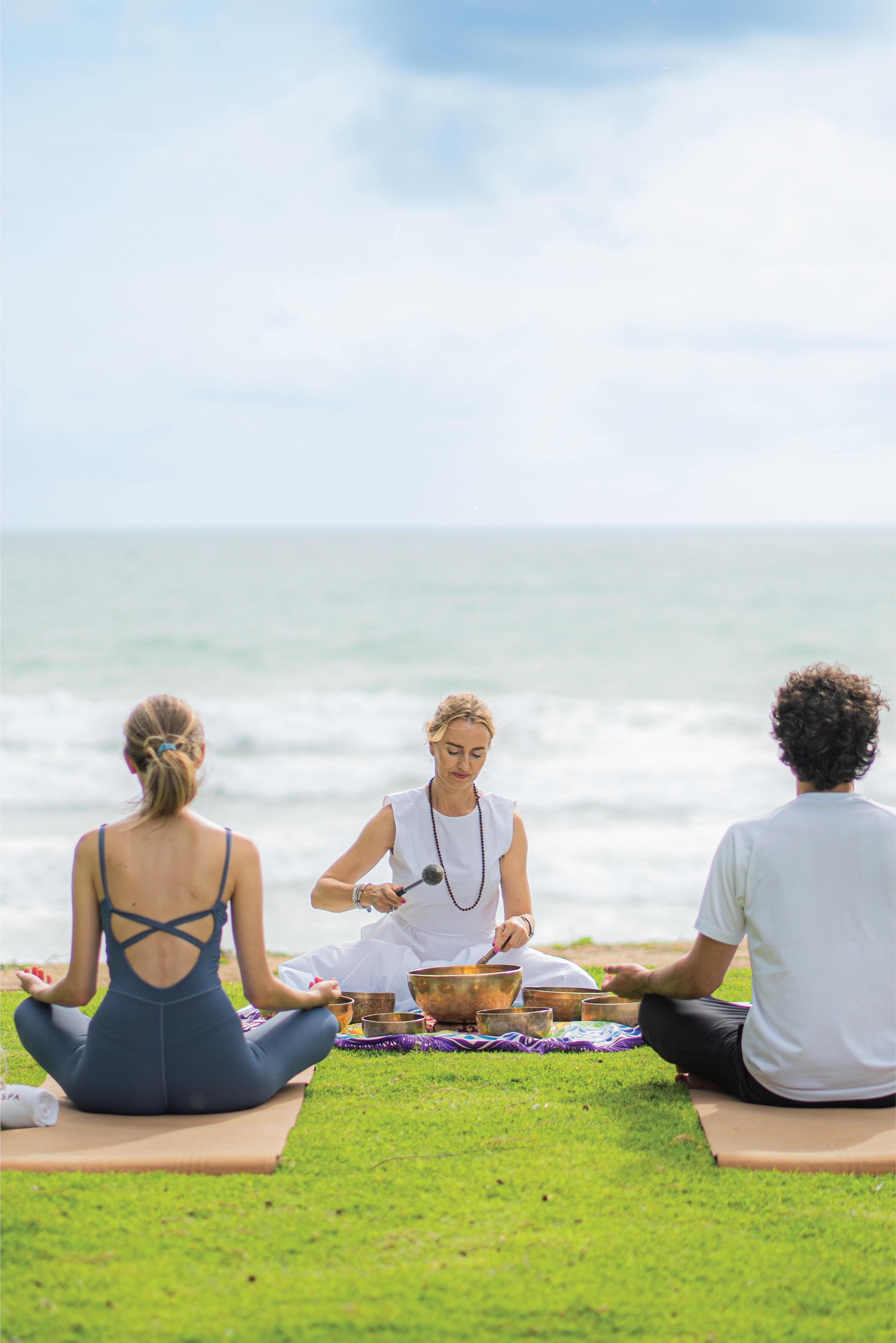 a group of people sitting on grass by the ocean