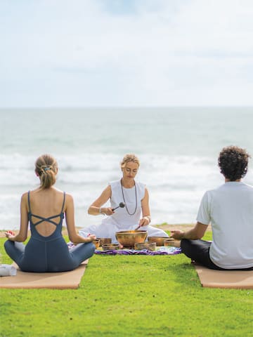 a group of people sitting on grass by the ocean