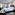 Modern hotel room with king bed, striped headboard, work desk, and window view.