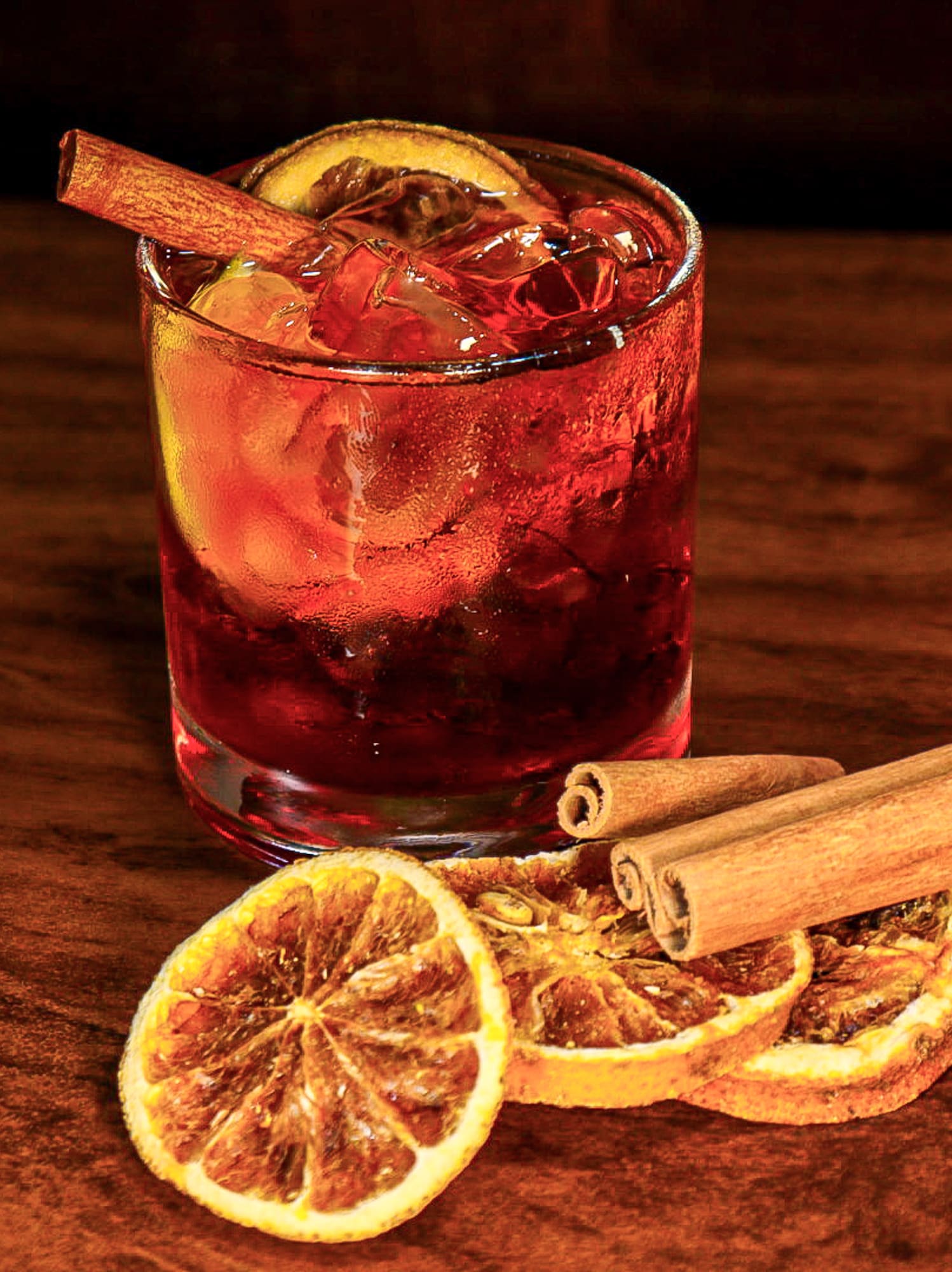 a glass of drink with a slice of orange and cinnamon