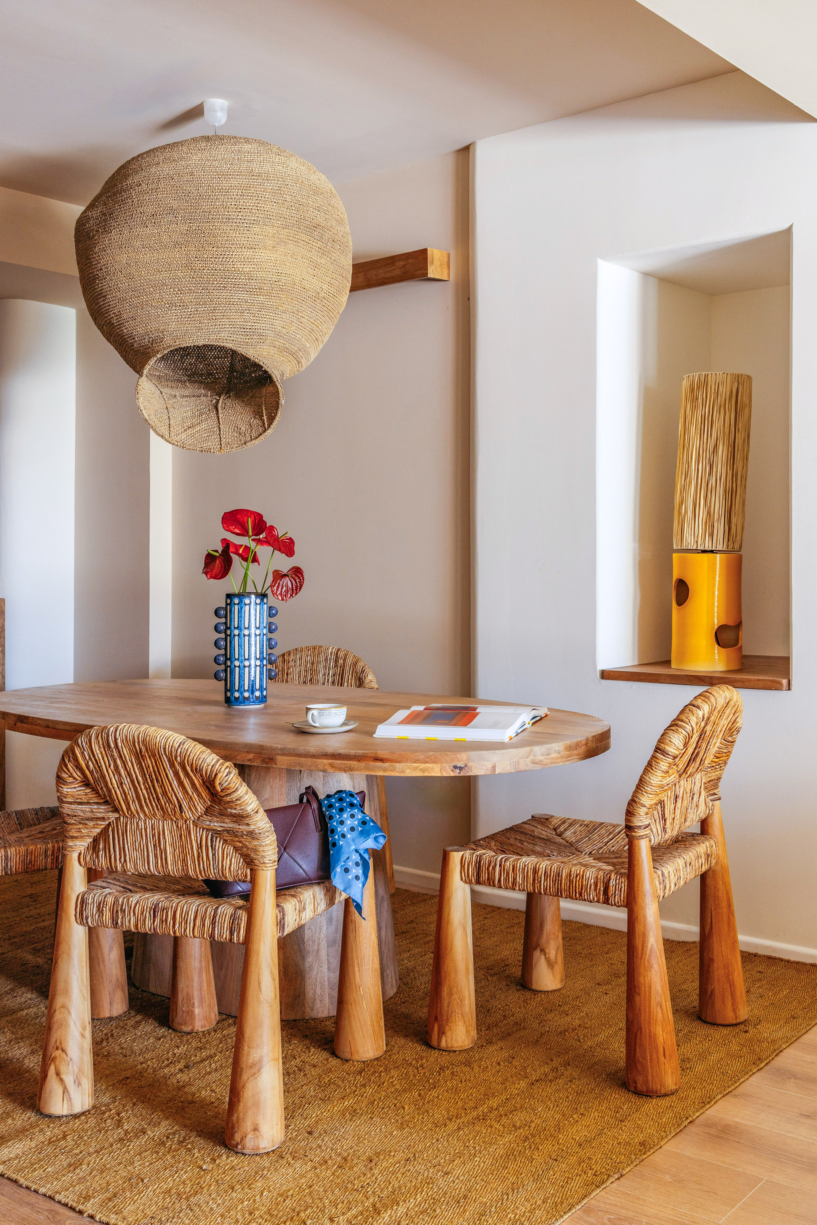 Organic dining room with wood table, woven chairs, and large natural fiber pendant.