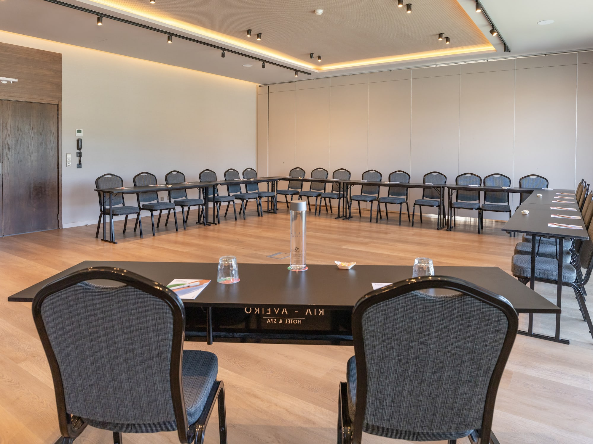 Modern hotel conference room with U-shaped table setup and chairs.