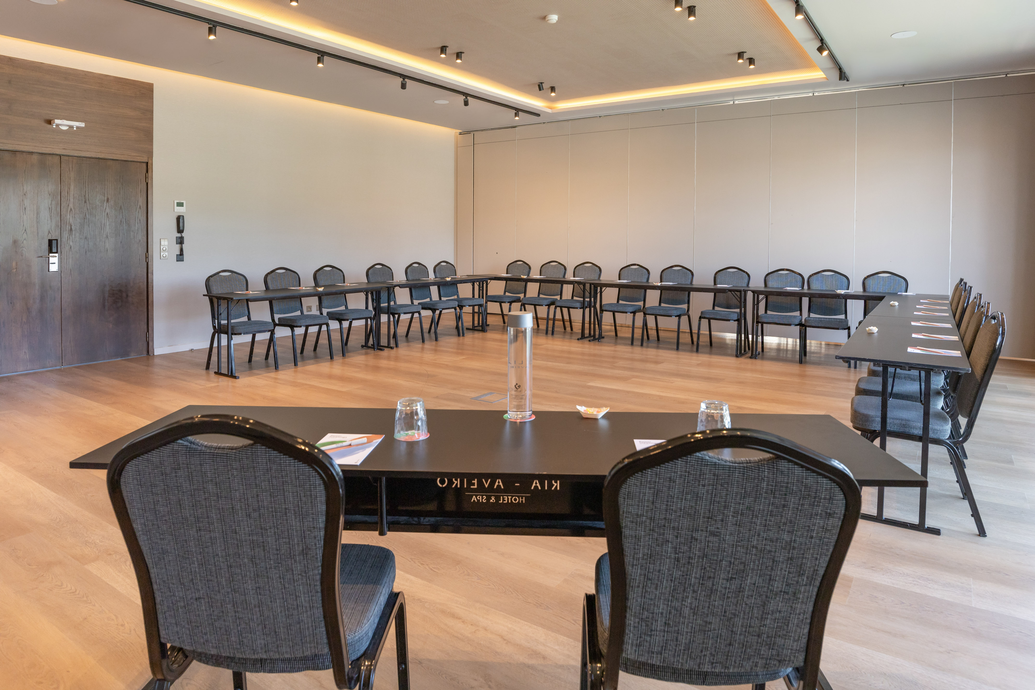 Modern hotel conference room with U-shaped table setup and chairs.