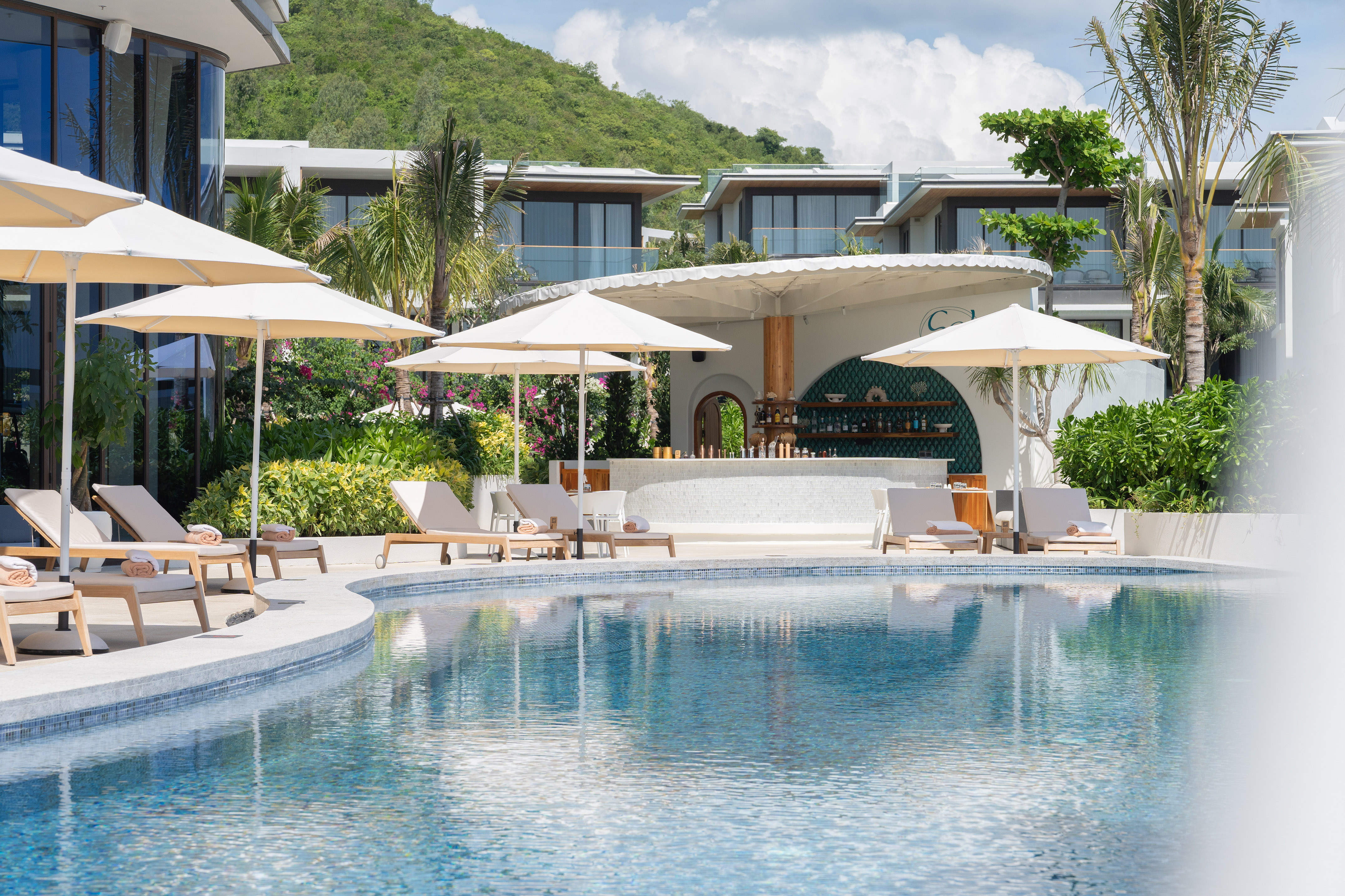 Luxury resort pool with sun loungers, tropical bar, and modern villas.