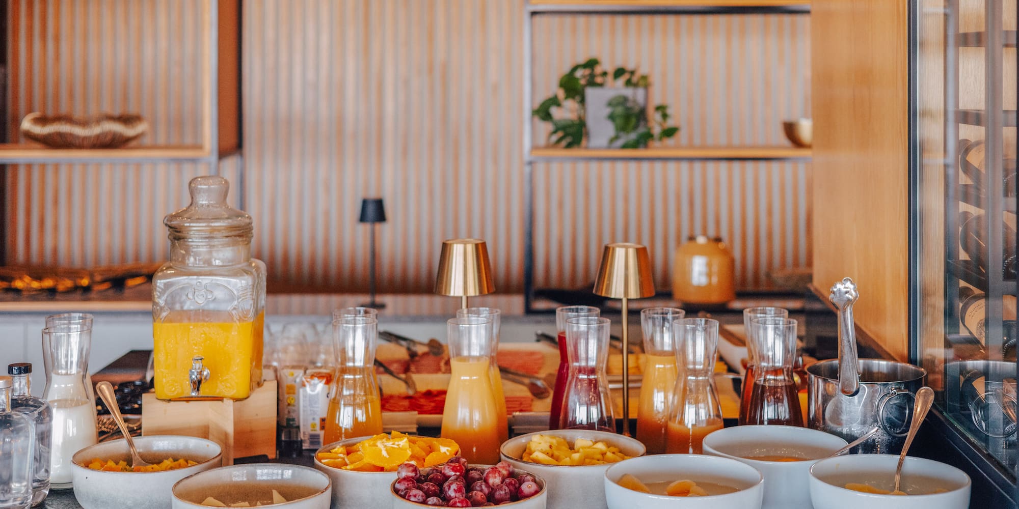 Hotel breakfast buffet with fresh juices, fruit bowls, and elegant decor.