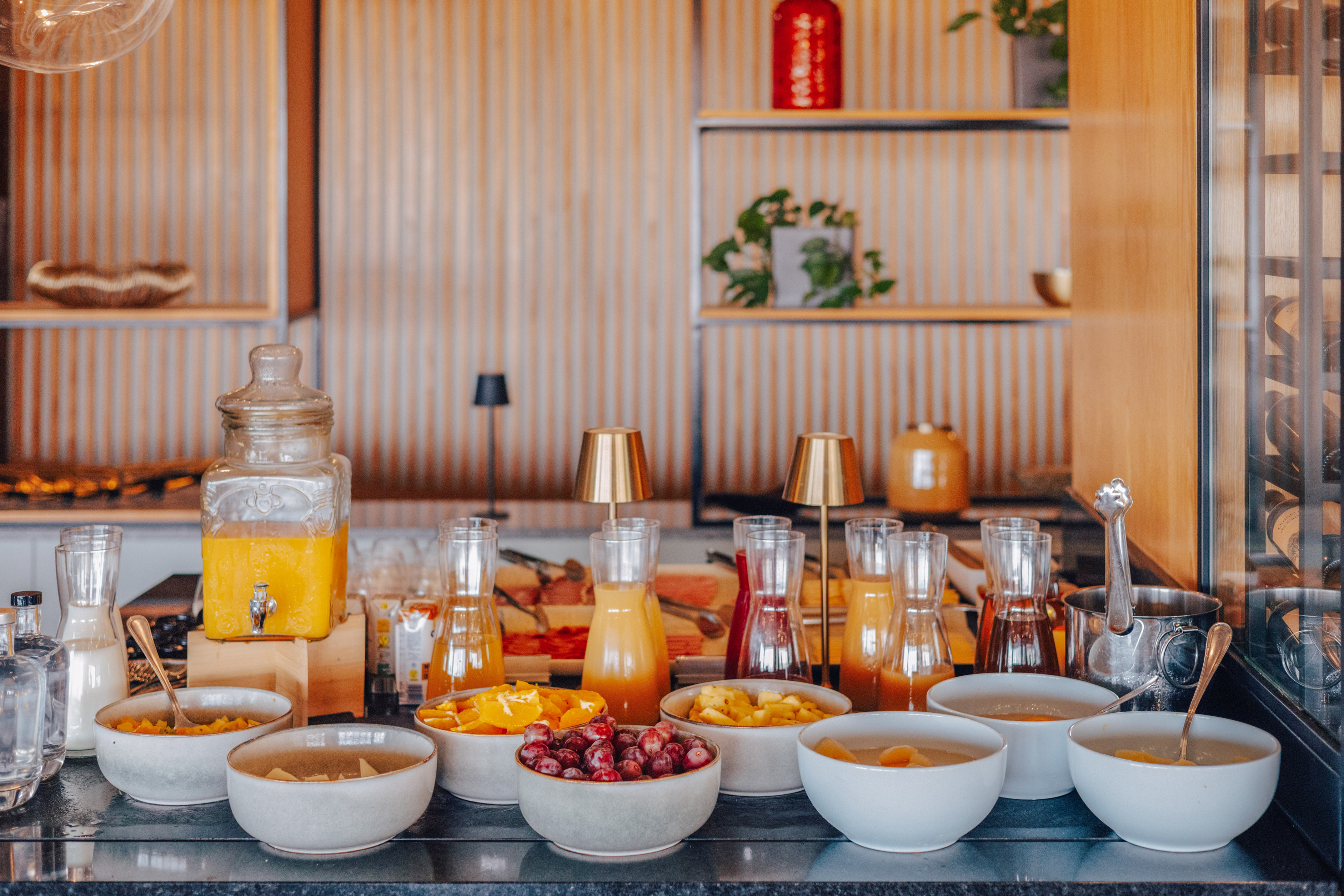 Hotel breakfast buffet with fresh juices, fruit bowls, and elegant decor.