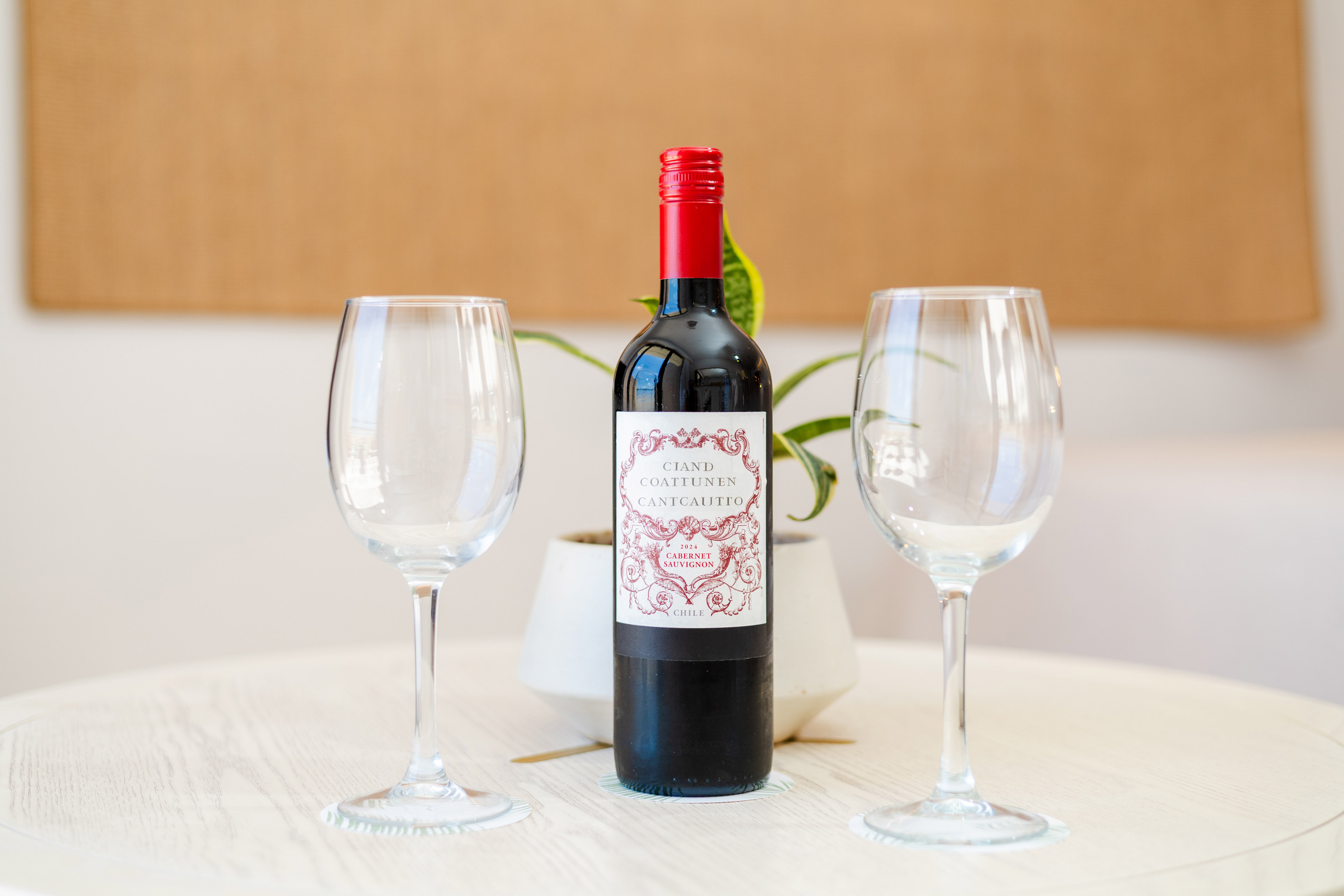 Chilean Cabernet Sauvignon red wine bottle with two empty glasses on a table.