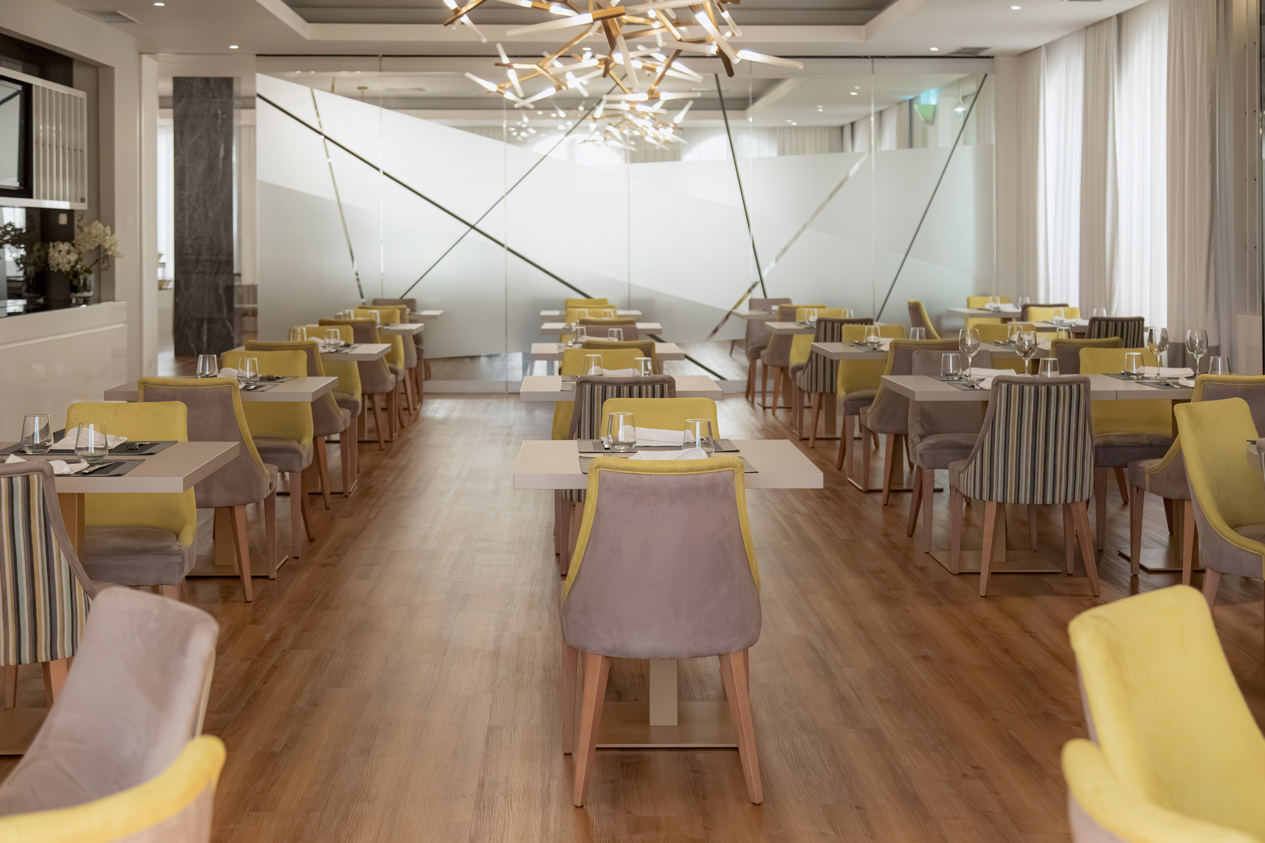 Elegant modern restaurant dining room with yellow and grey chairs.