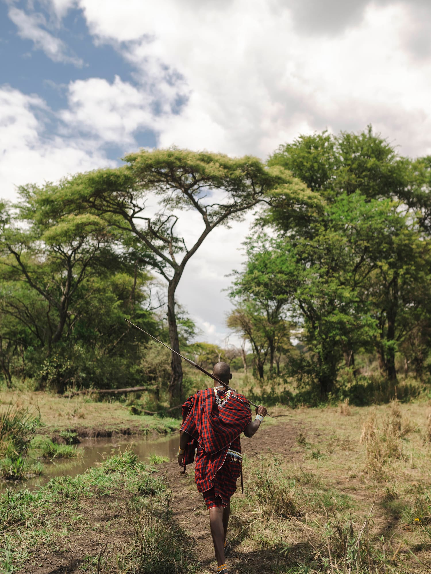 a man in a red and black robe walking through a forest