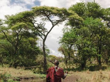 a man in a red and black robe walking through a forest