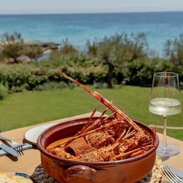 a bowl of lobster on a table with a glass of wine