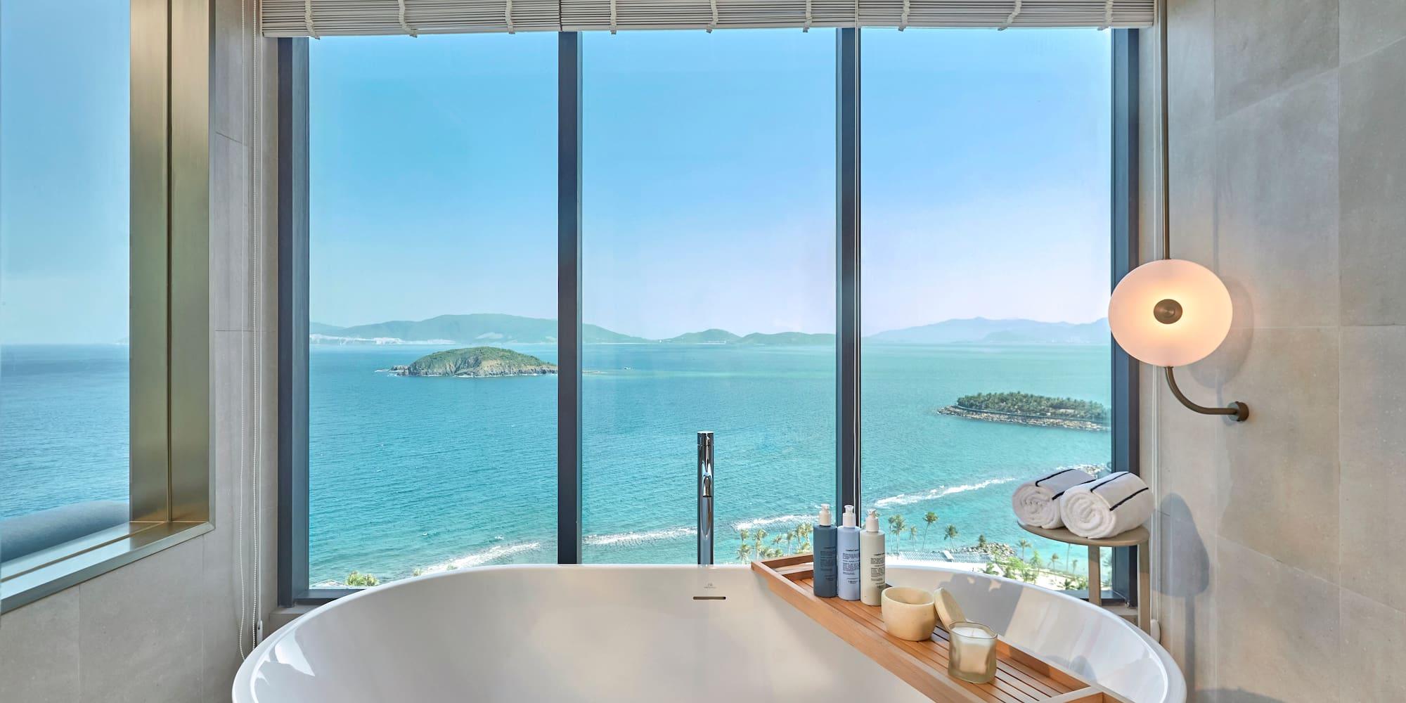 Luxury bathroom with ocean view, freestanding tub, and coastal islands.