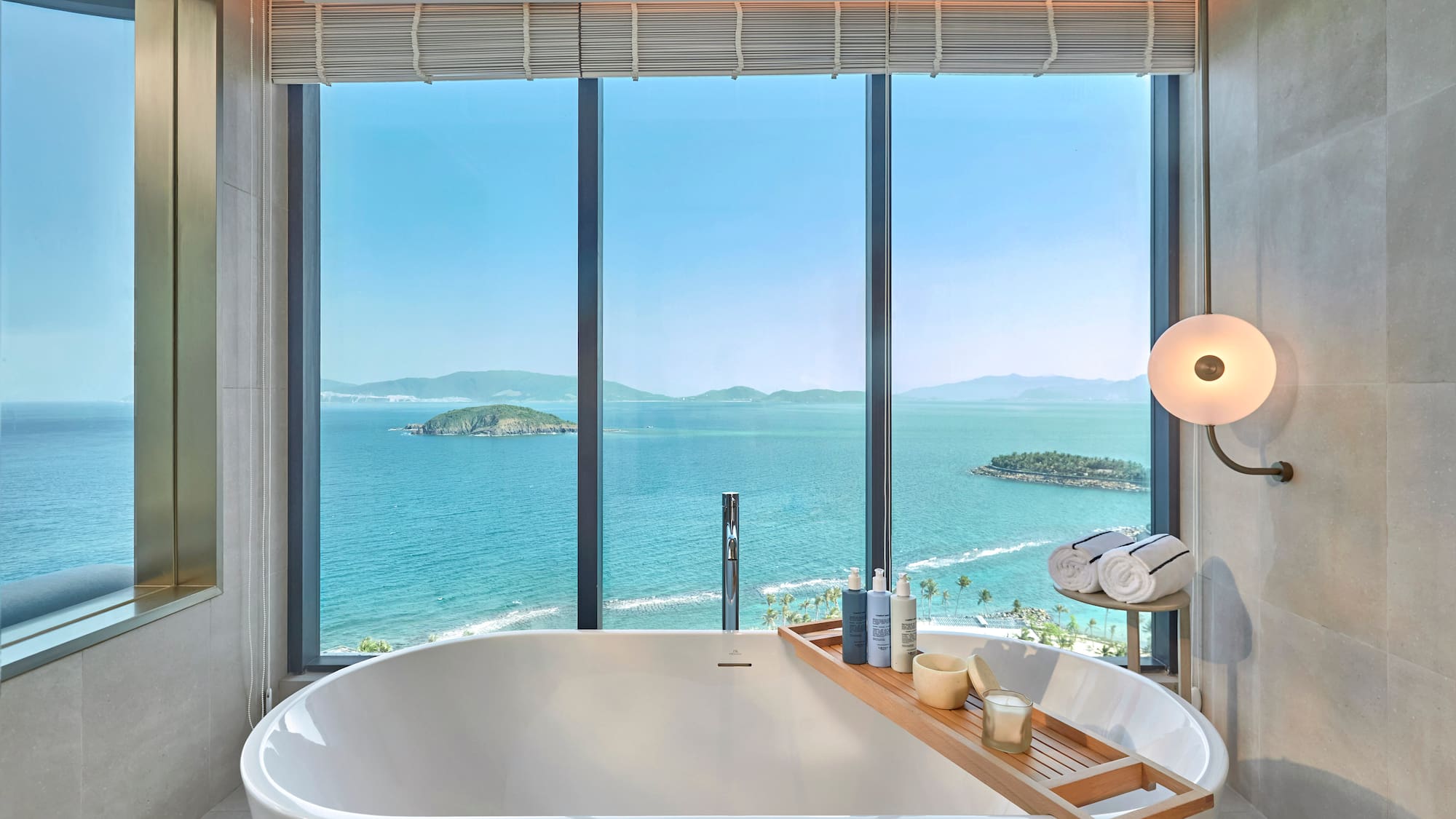 Luxury bathroom with ocean view, freestanding tub, and coastal islands.