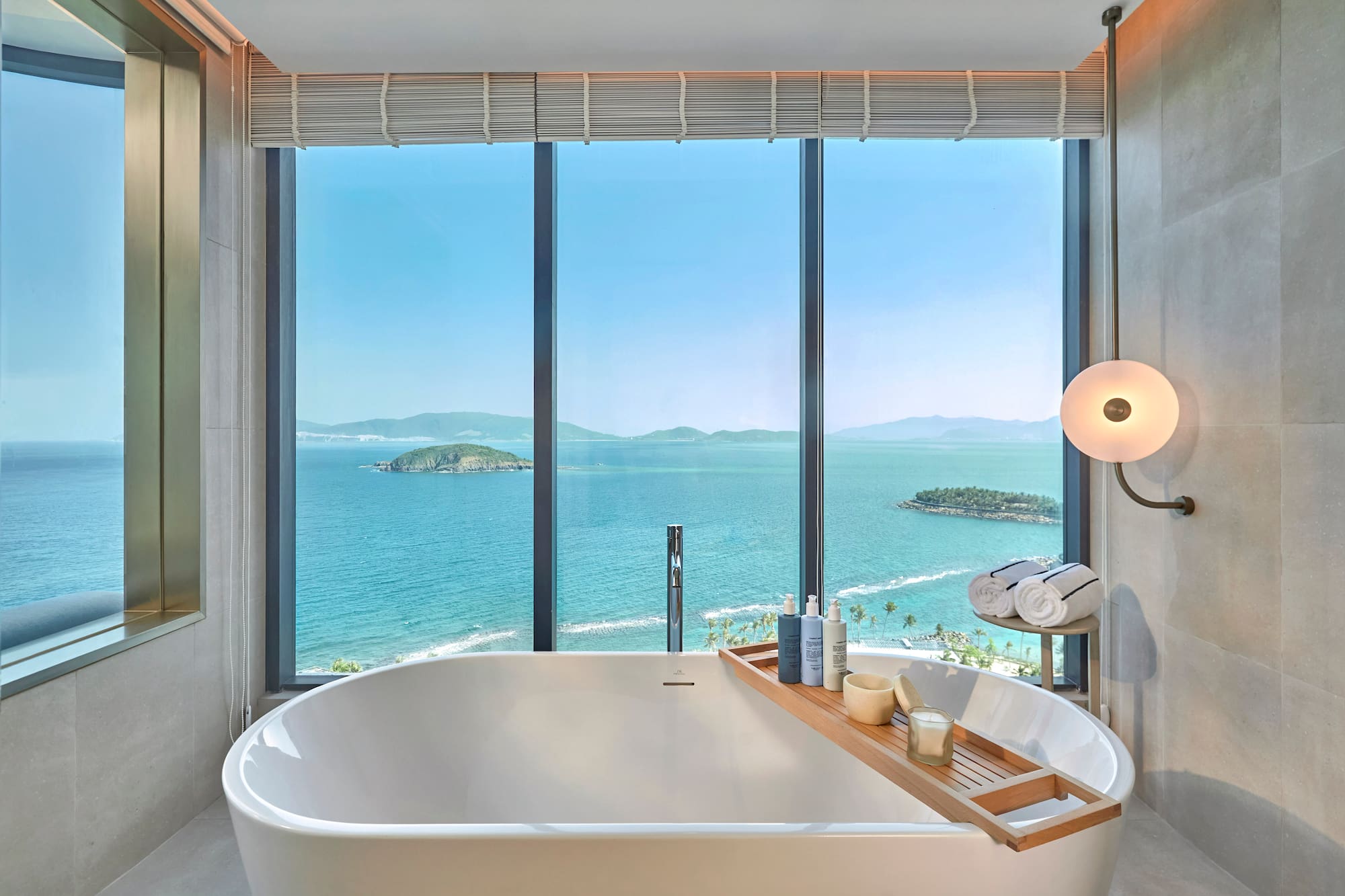 Luxury bathroom with ocean view, freestanding tub, and coastal islands.