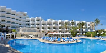 a pool with chairs and umbrellas in front of a hotel