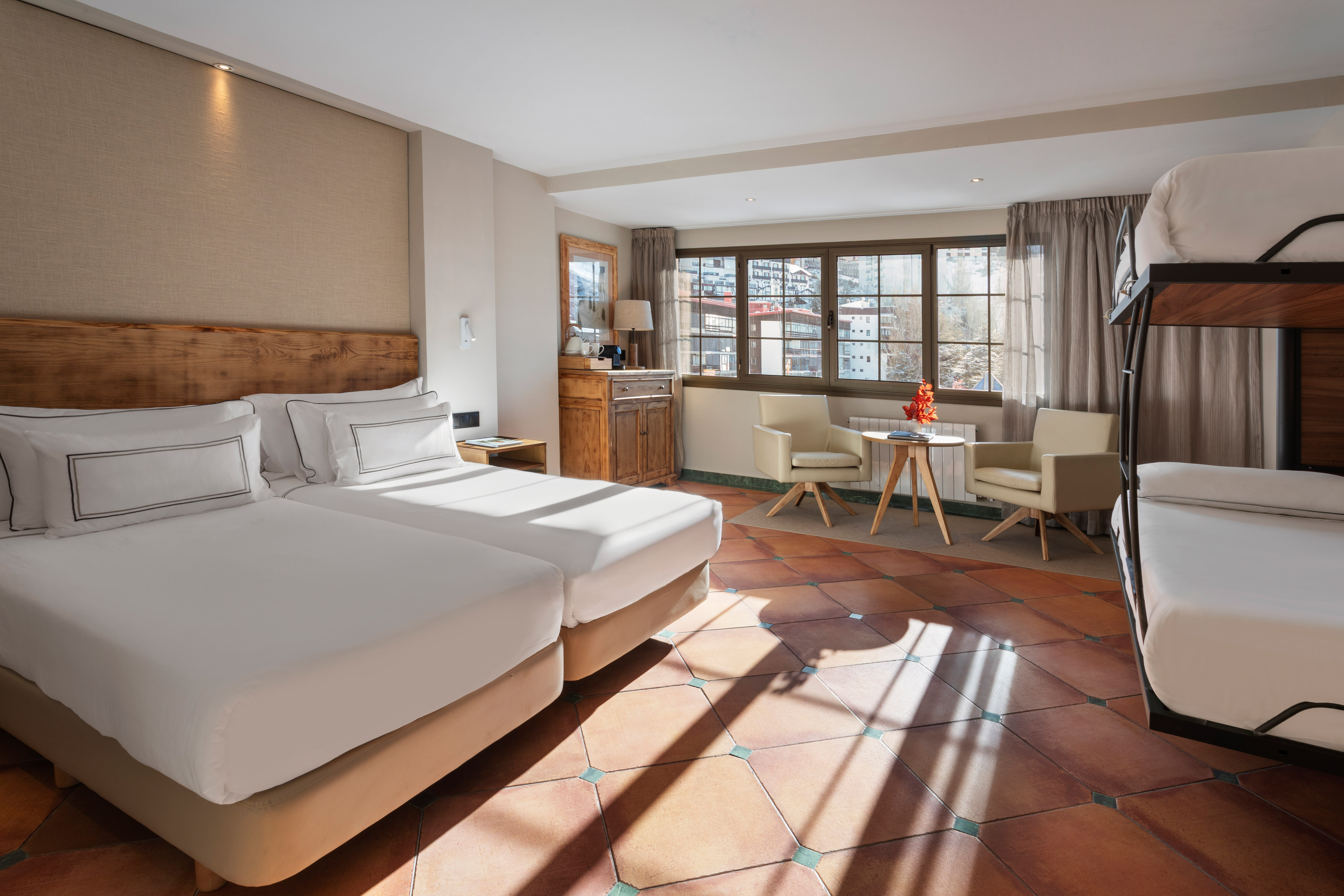 Hotel family room with twin beds, bunk bed, mountain view, terracotta floor.