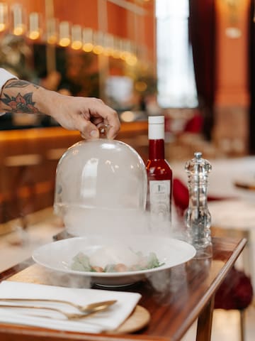 a person holding a glass dome over a plate of food