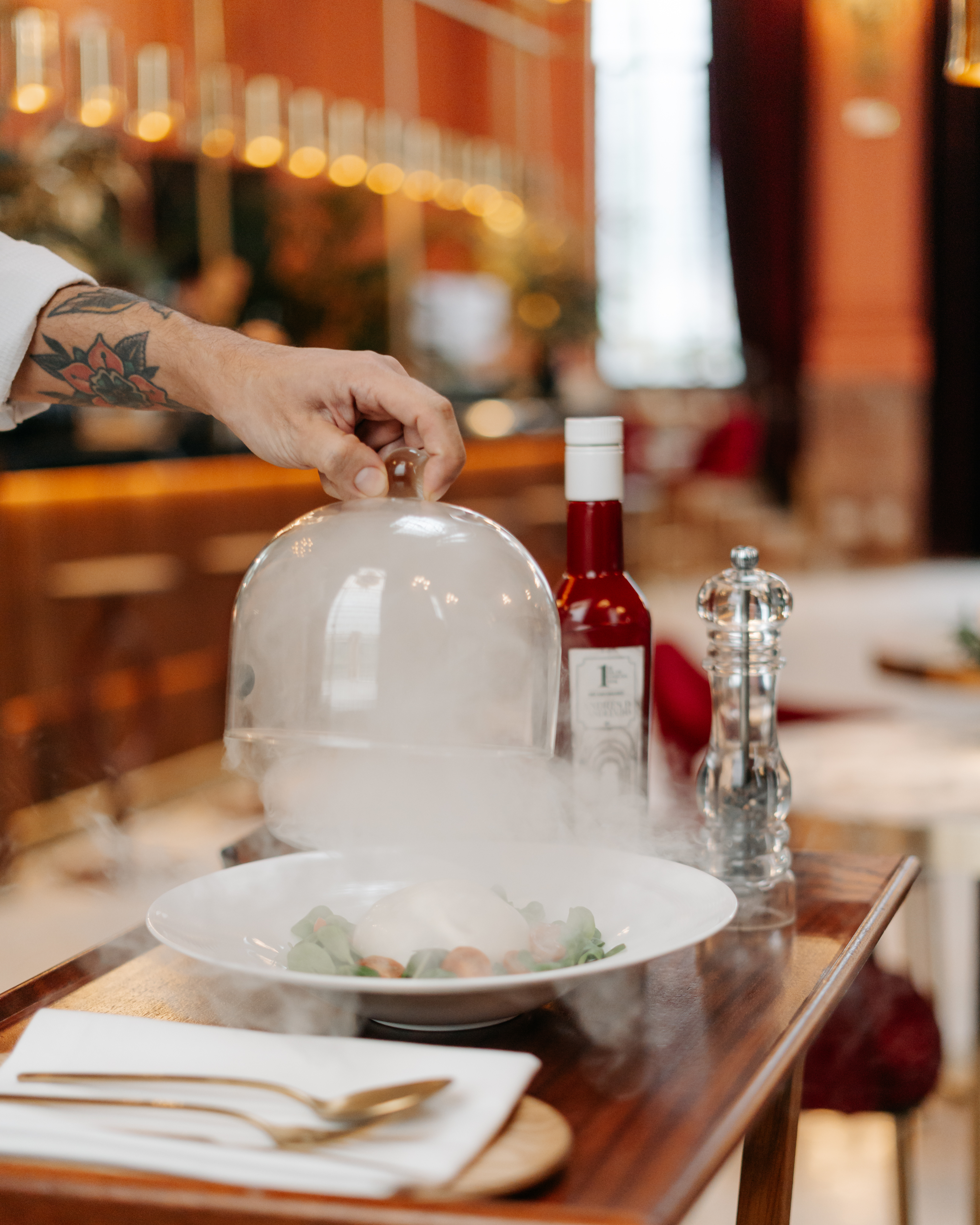 a person holding a glass dome over a plate of food