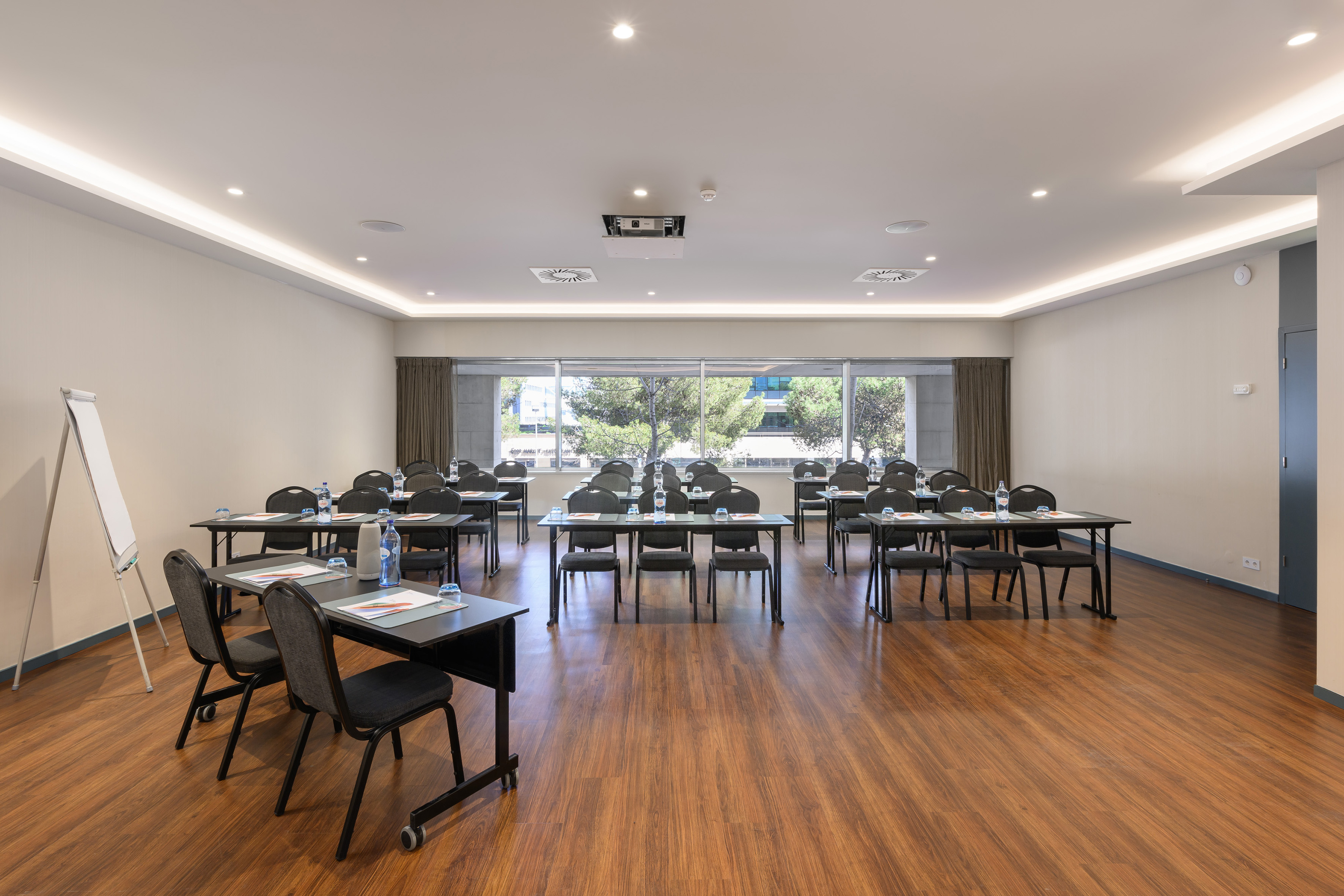 Modern conference room with tables, chairs, projector, and natural light.