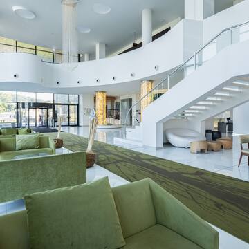 a large white room with green couches and stairs