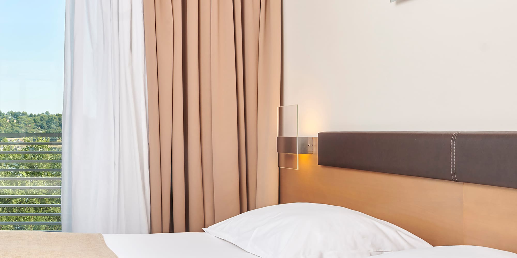 a bed with white pillows and brown headboard in a hotel room