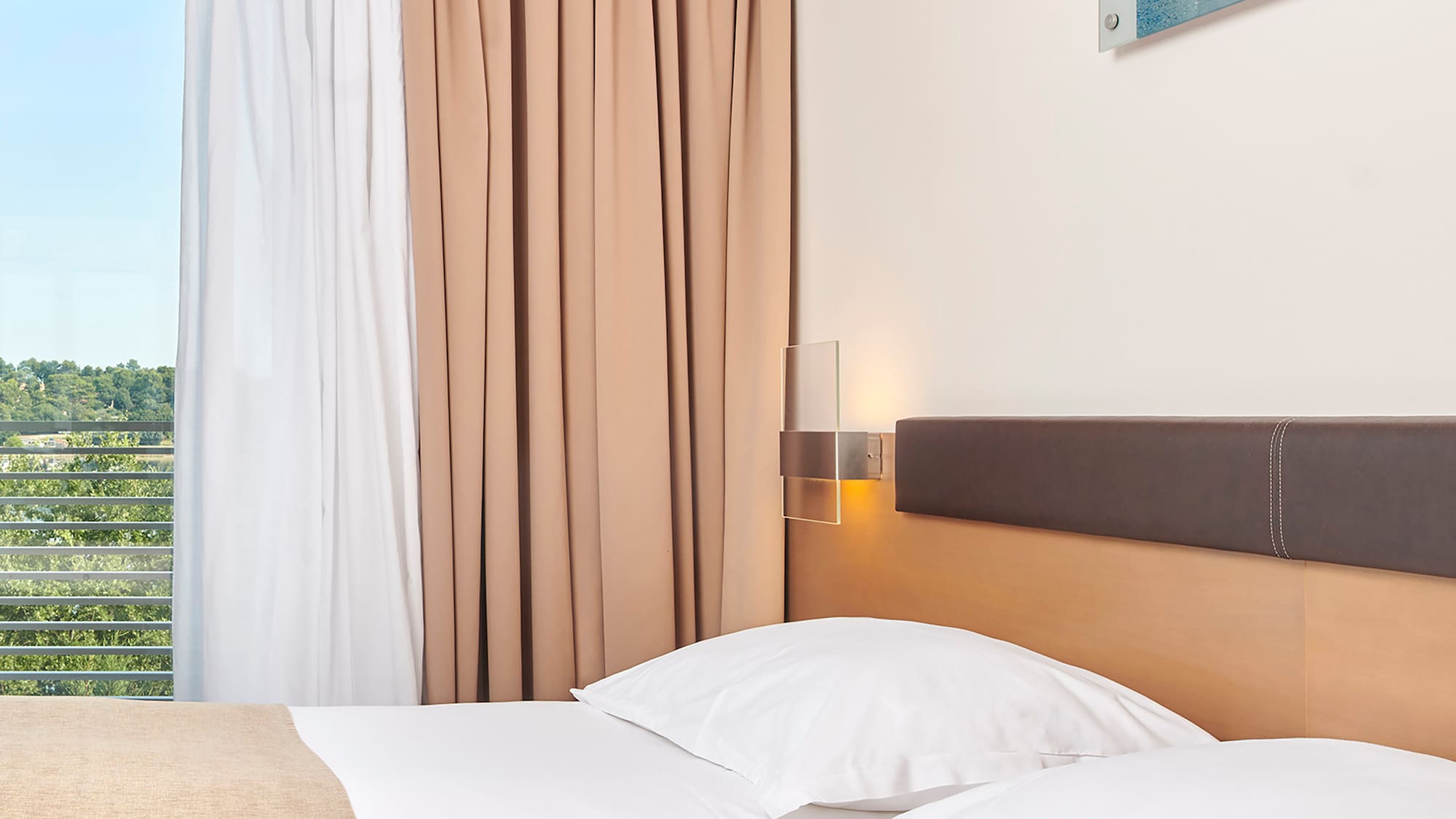 a bed with white pillows and brown headboard in a hotel room