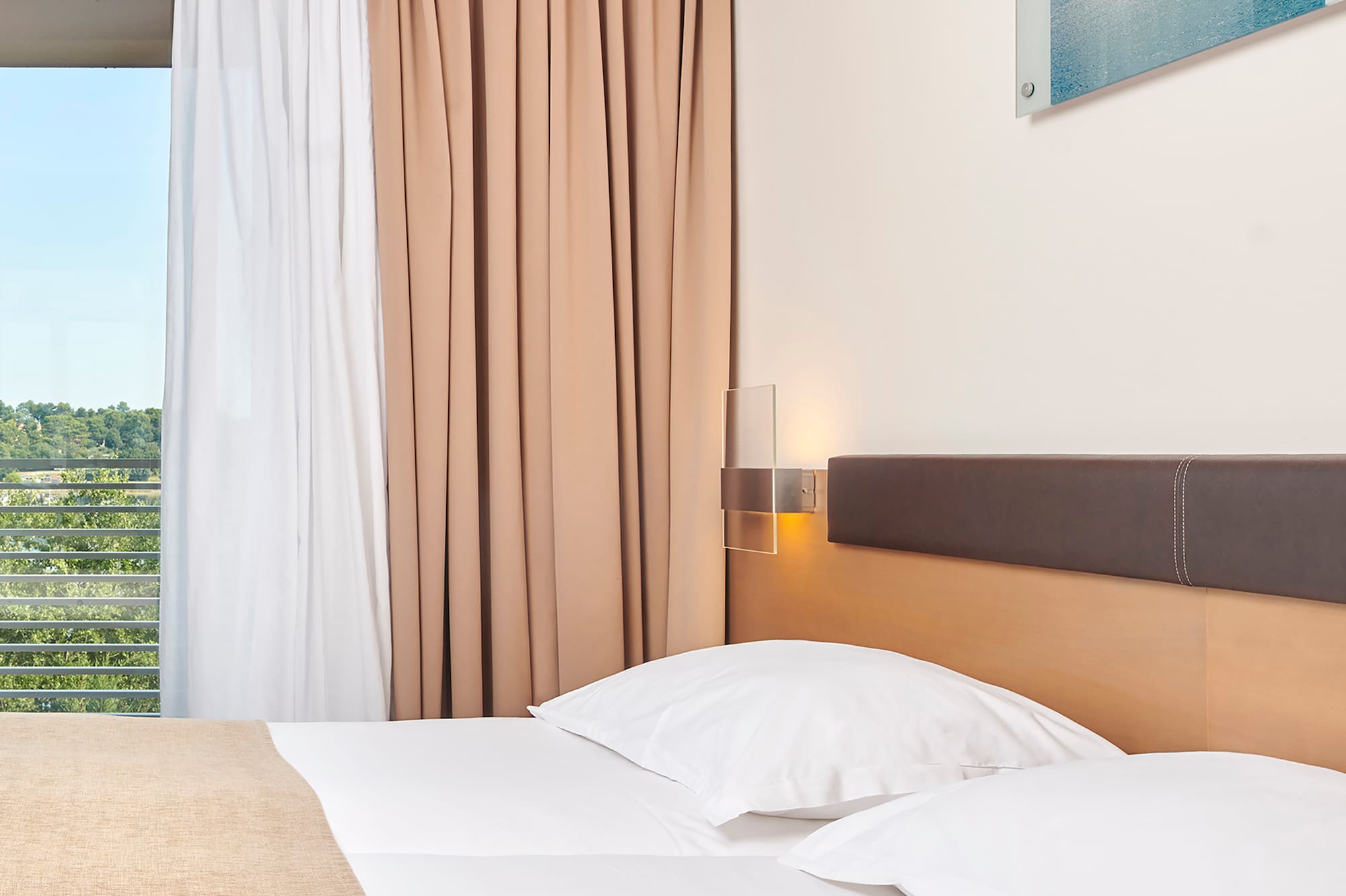 a bed with white pillows and brown headboard in a hotel room