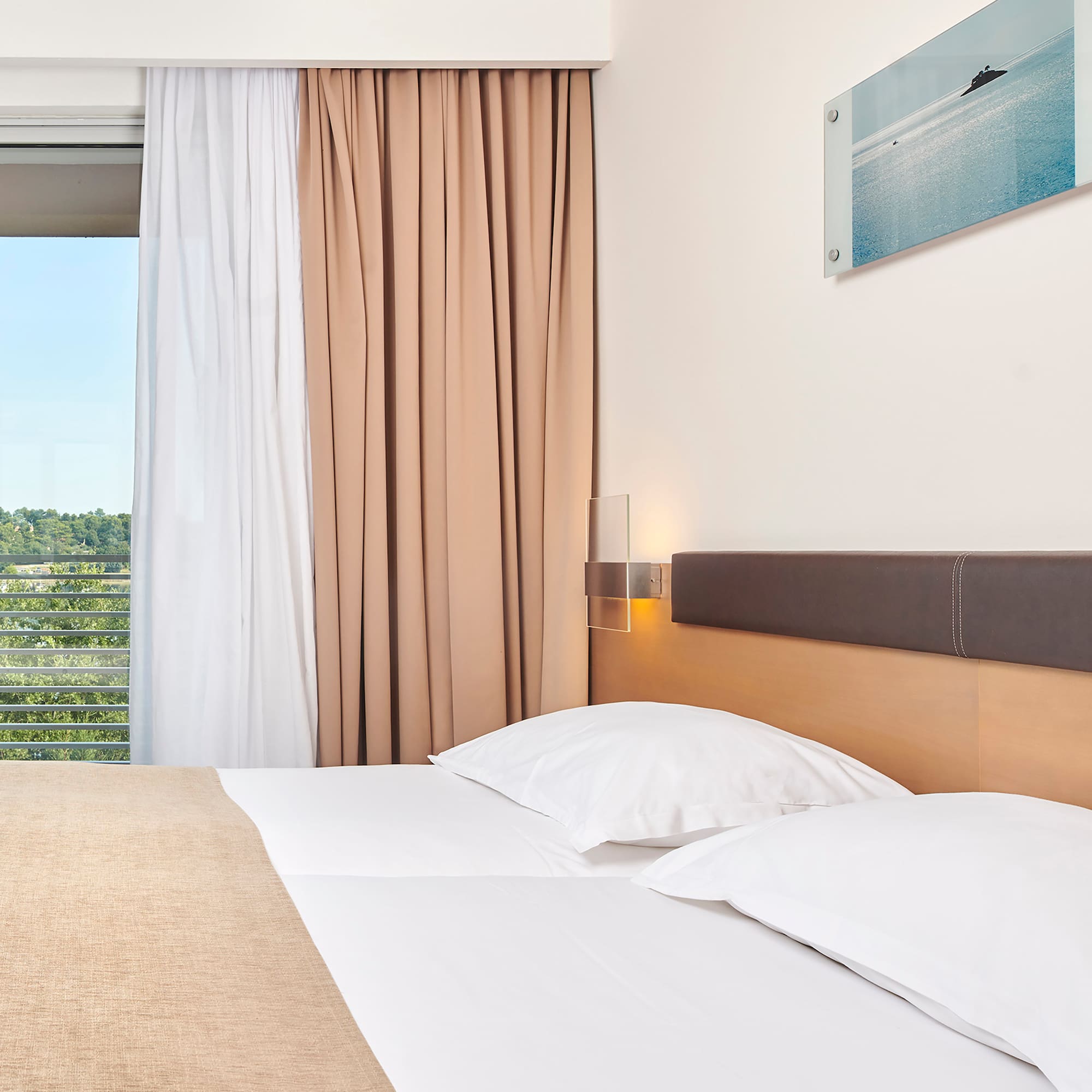 a bed with white pillows and brown headboard in a hotel room