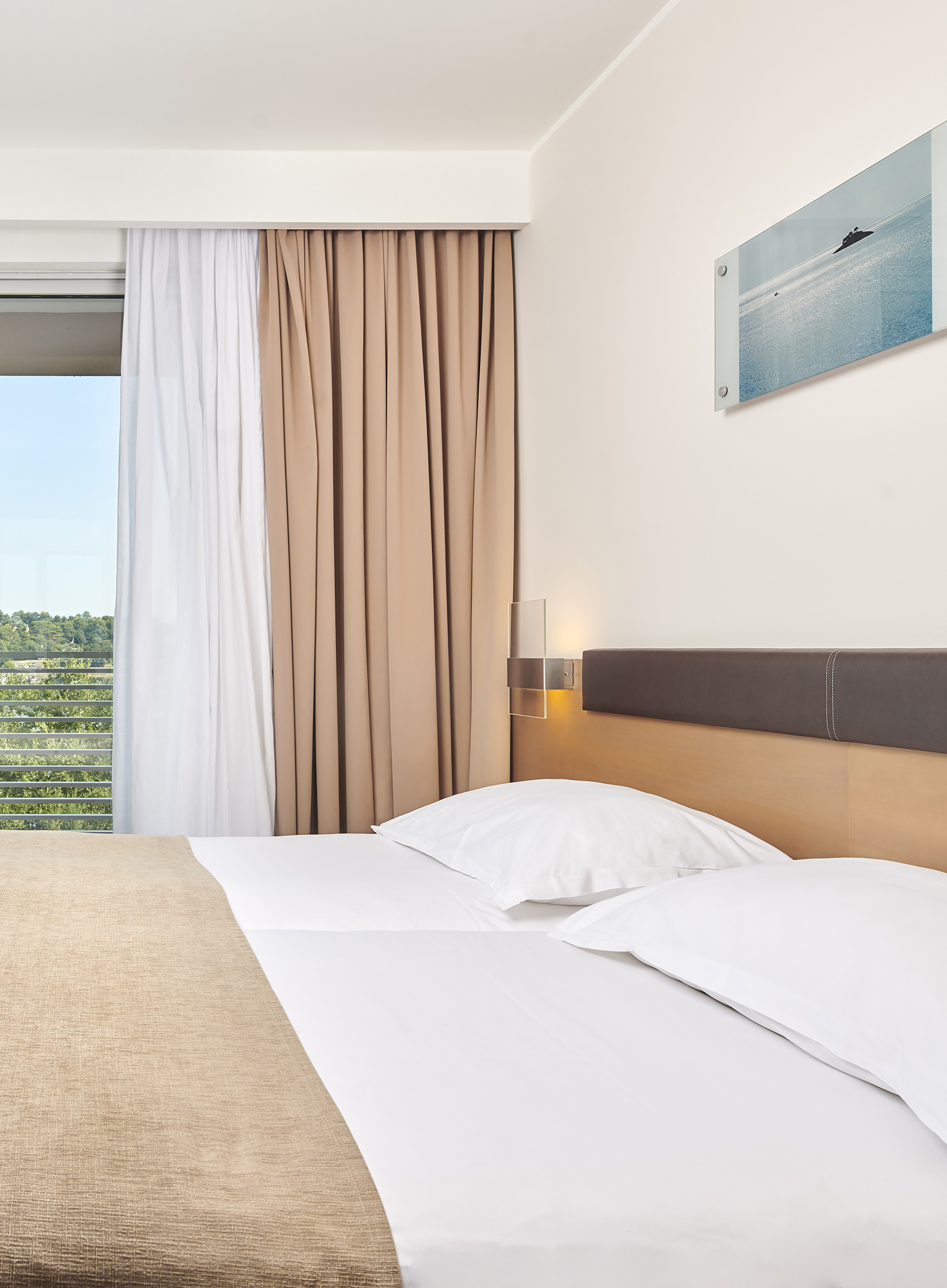 a bed with white pillows and brown headboard in a hotel room