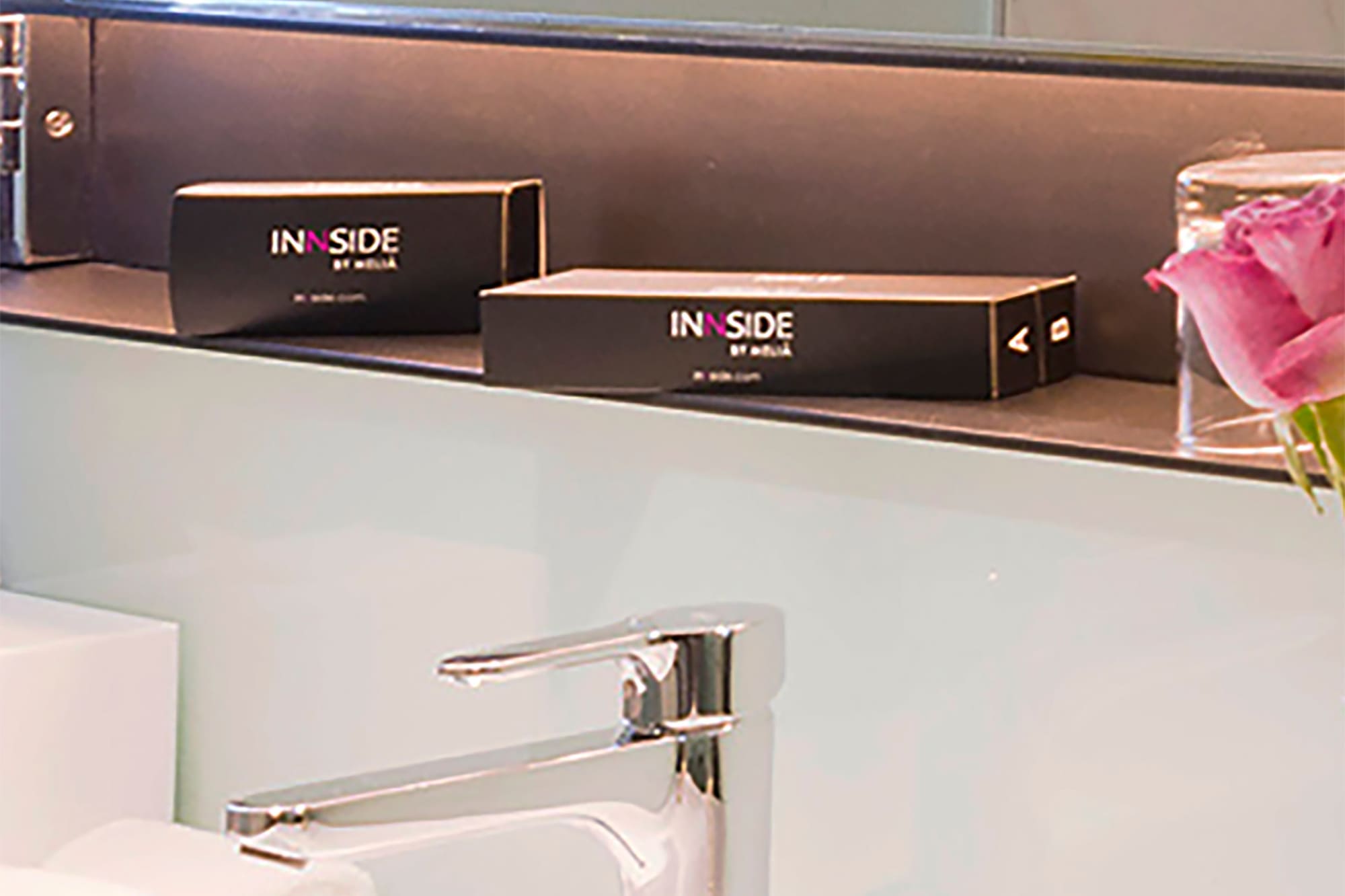 a bathroom sink with a mirror and a pink rose