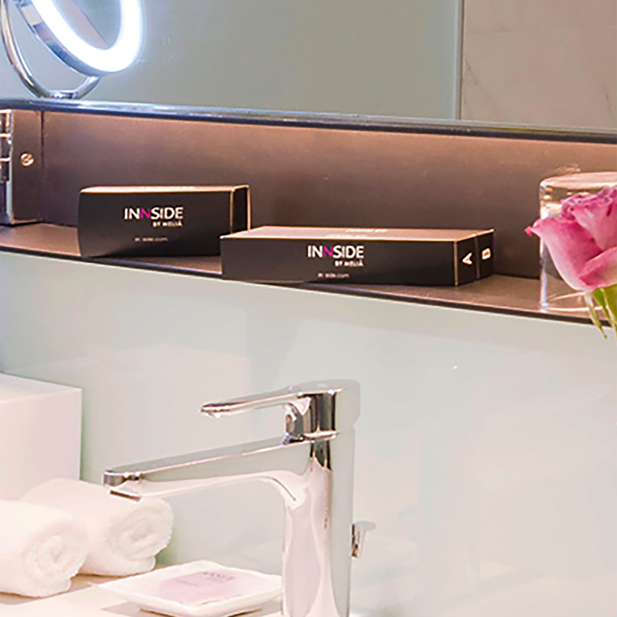a bathroom sink with a mirror and a pink rose