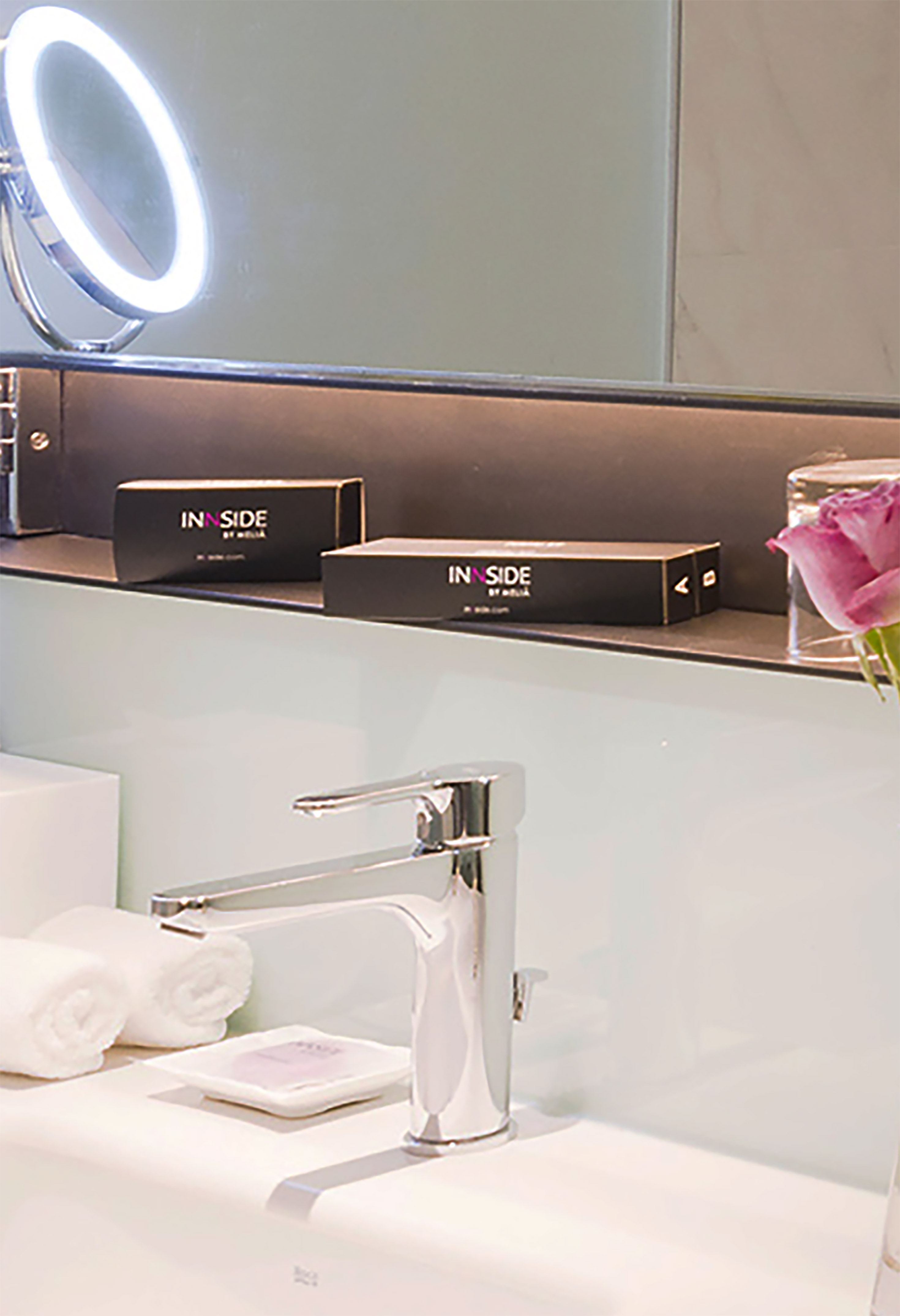 a bathroom sink with a mirror and a pink rose