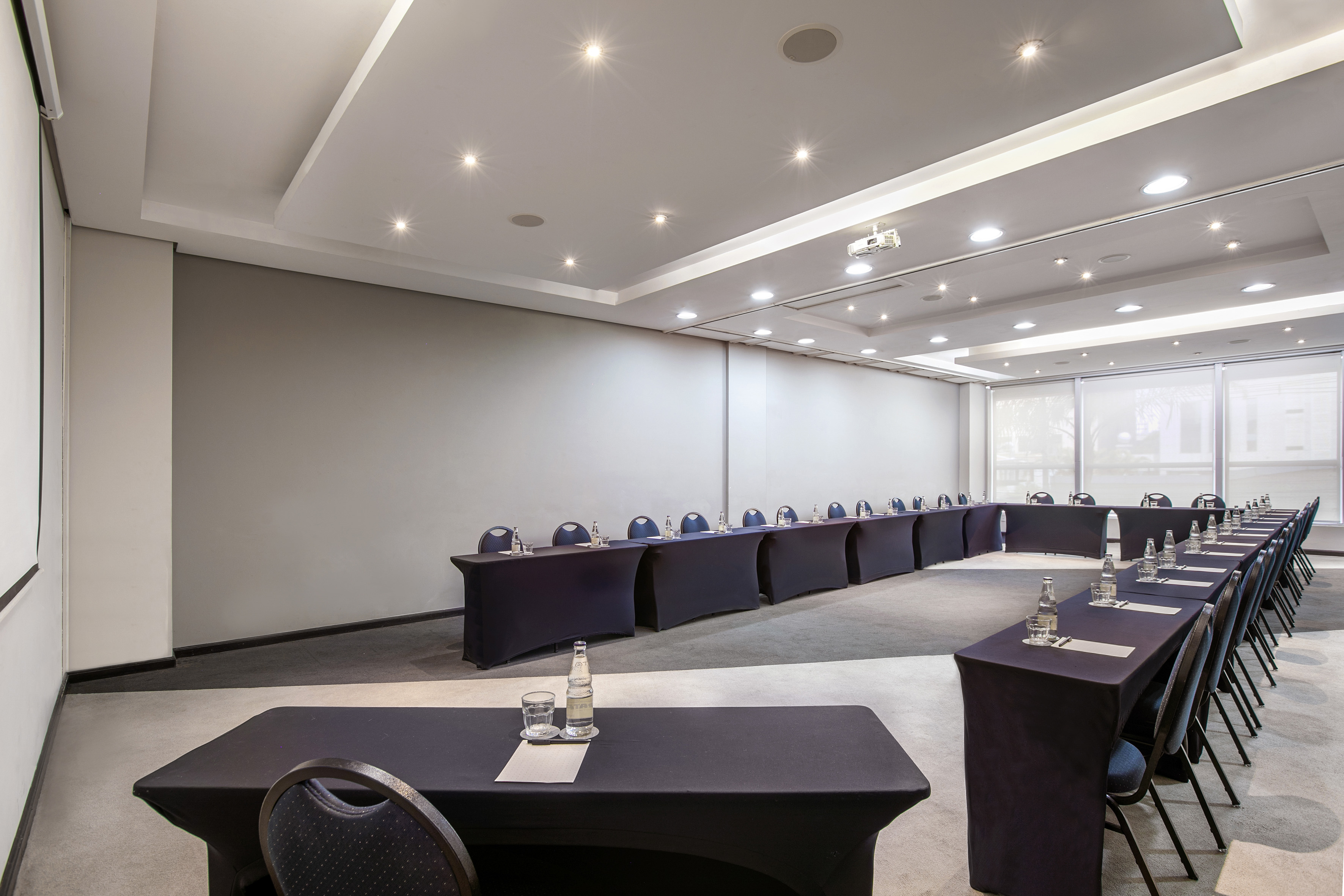 U-shaped conference room with projector, screen, and water bottles.