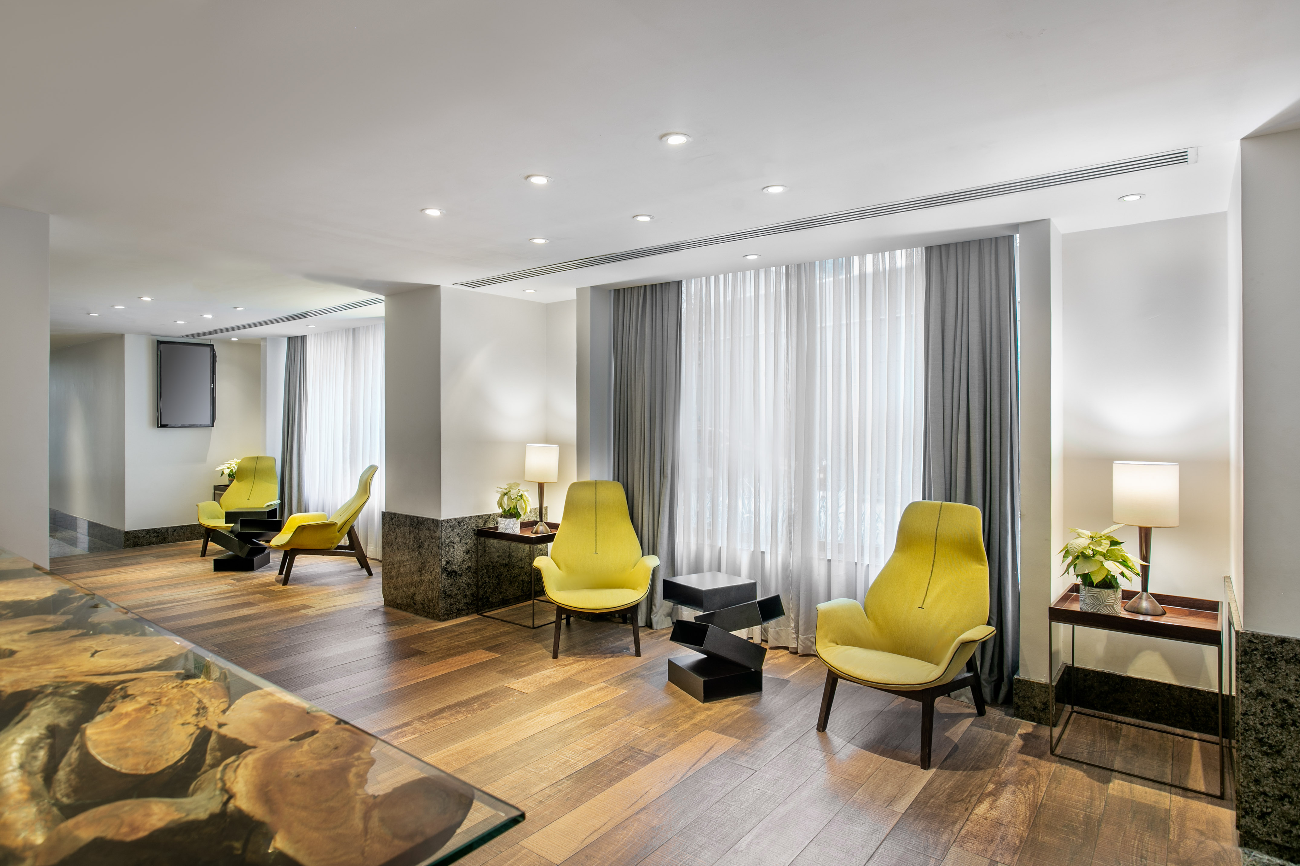Modern lounge with yellow armchairs, hardwood floor, and recessed lighting.