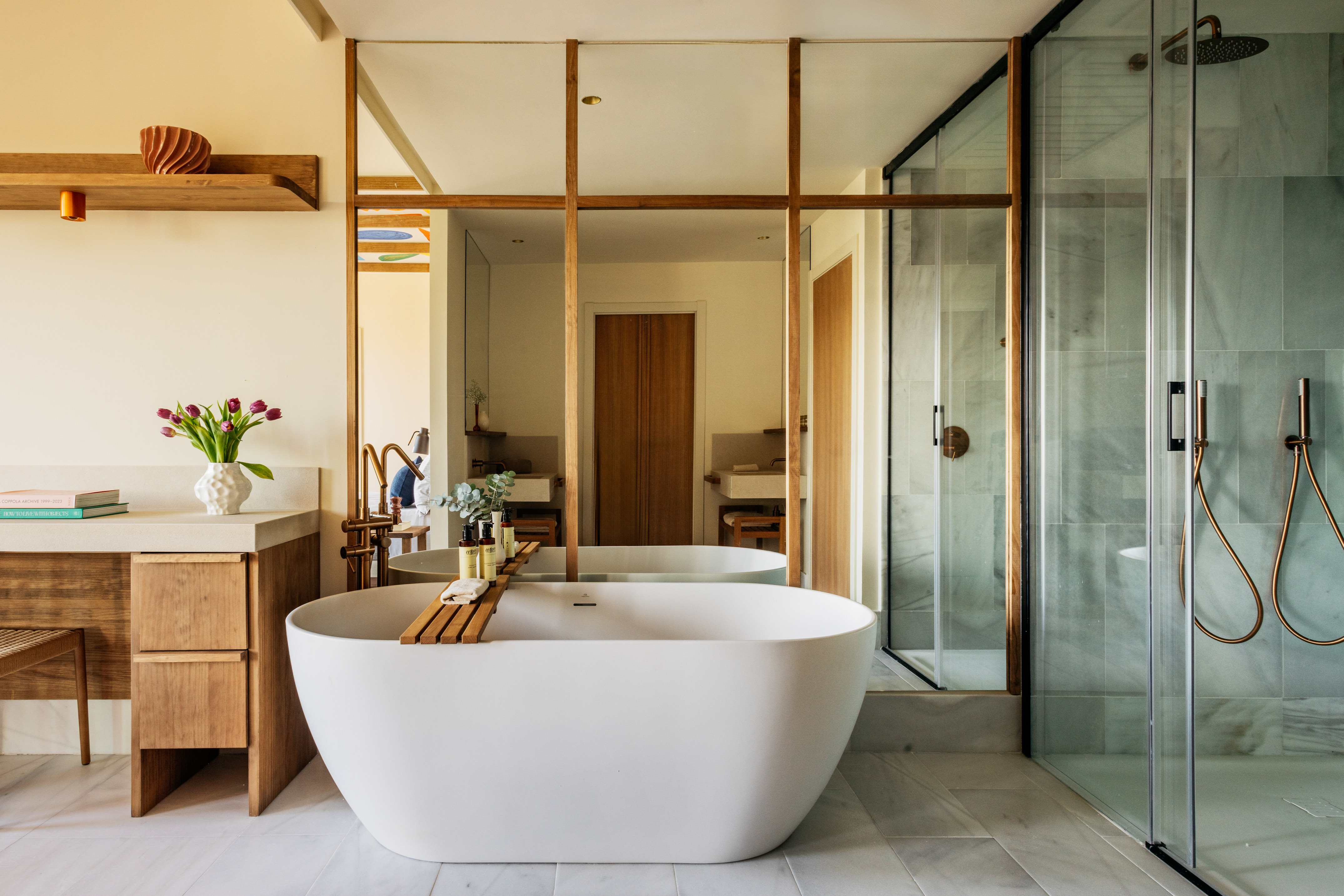 Contemporary bathroom with white freestanding tub, wood vanity, and walk-in shower.
